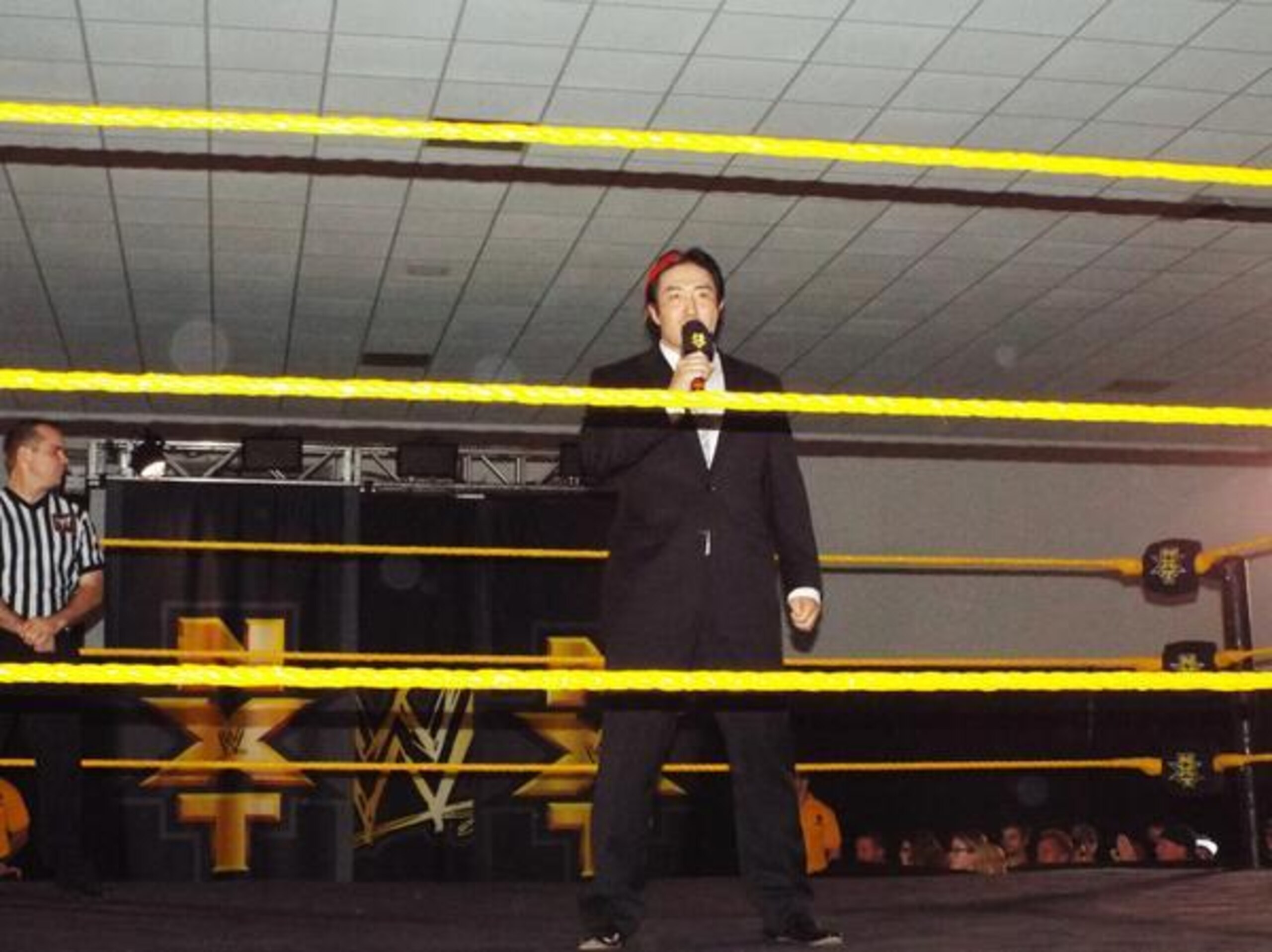 Yoshi Tatsu handles the ring announcing duties at an NXT live event.