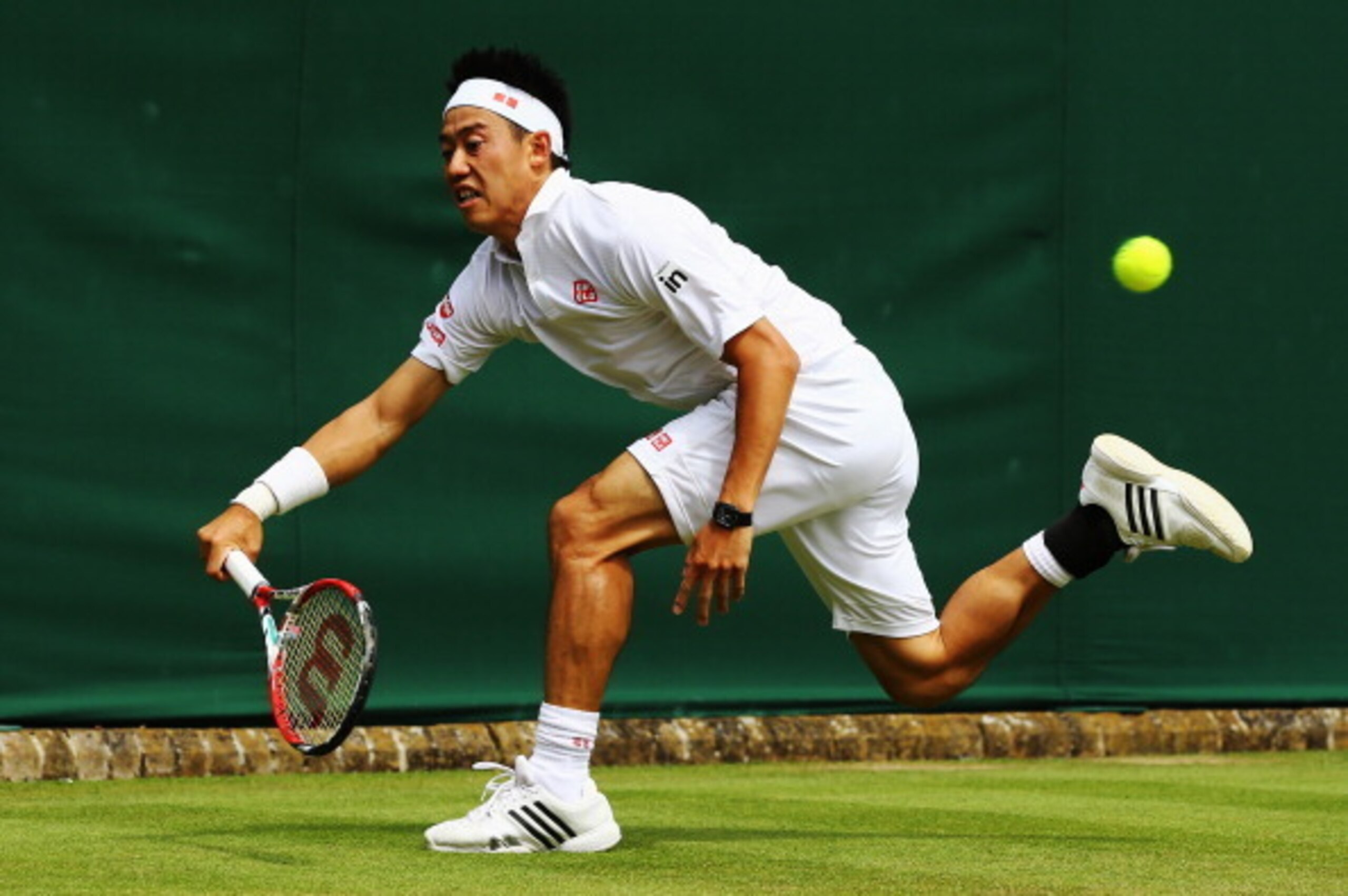 Kei Nishikori dashes to make a play on the ball during a match at 2014 Wimbledon.