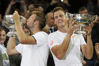 American Jack Sock kisses his Wimbledon trophy next to doubles partner Vasek Pospisil.