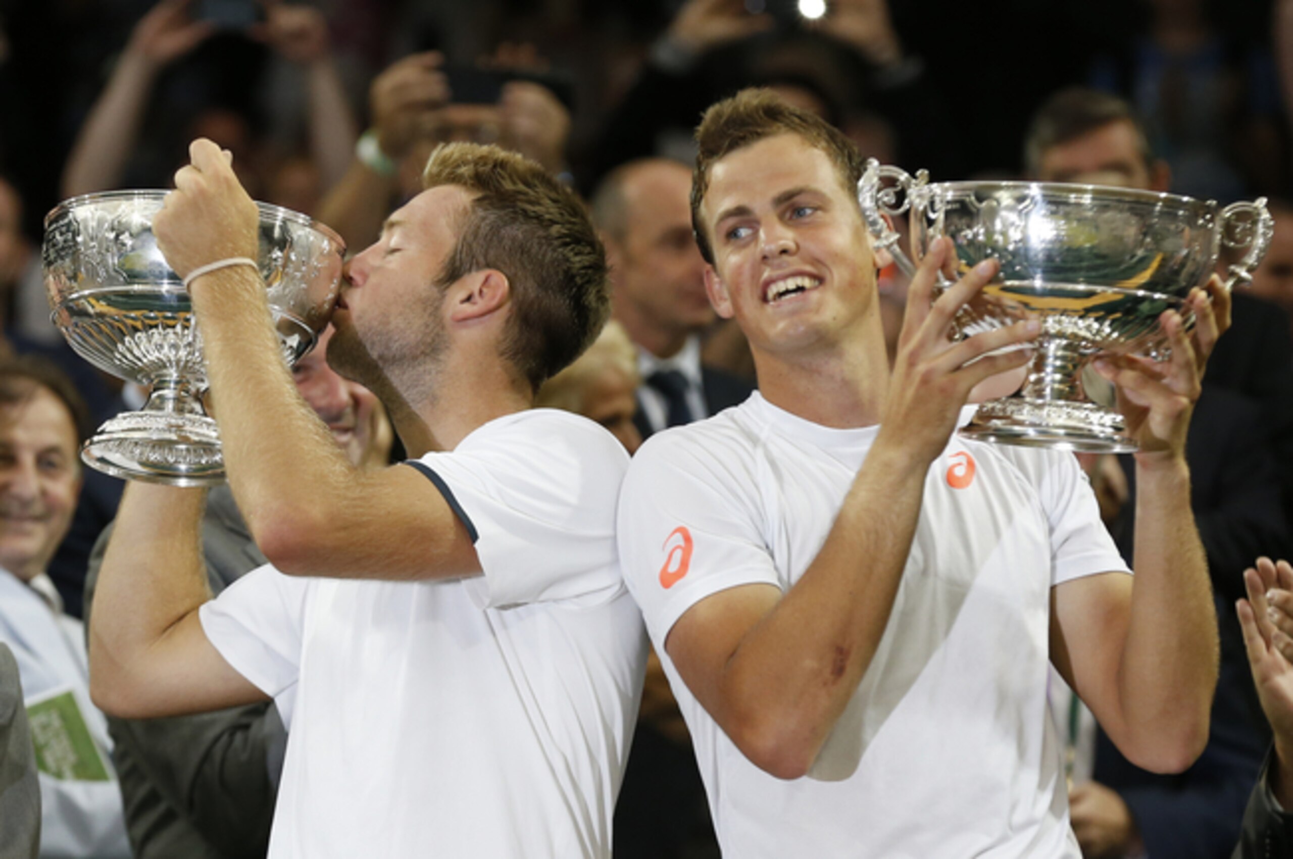 American Jack Sock kisses his Wimbledon trophy next to doubles partner Vasek Pospisil.