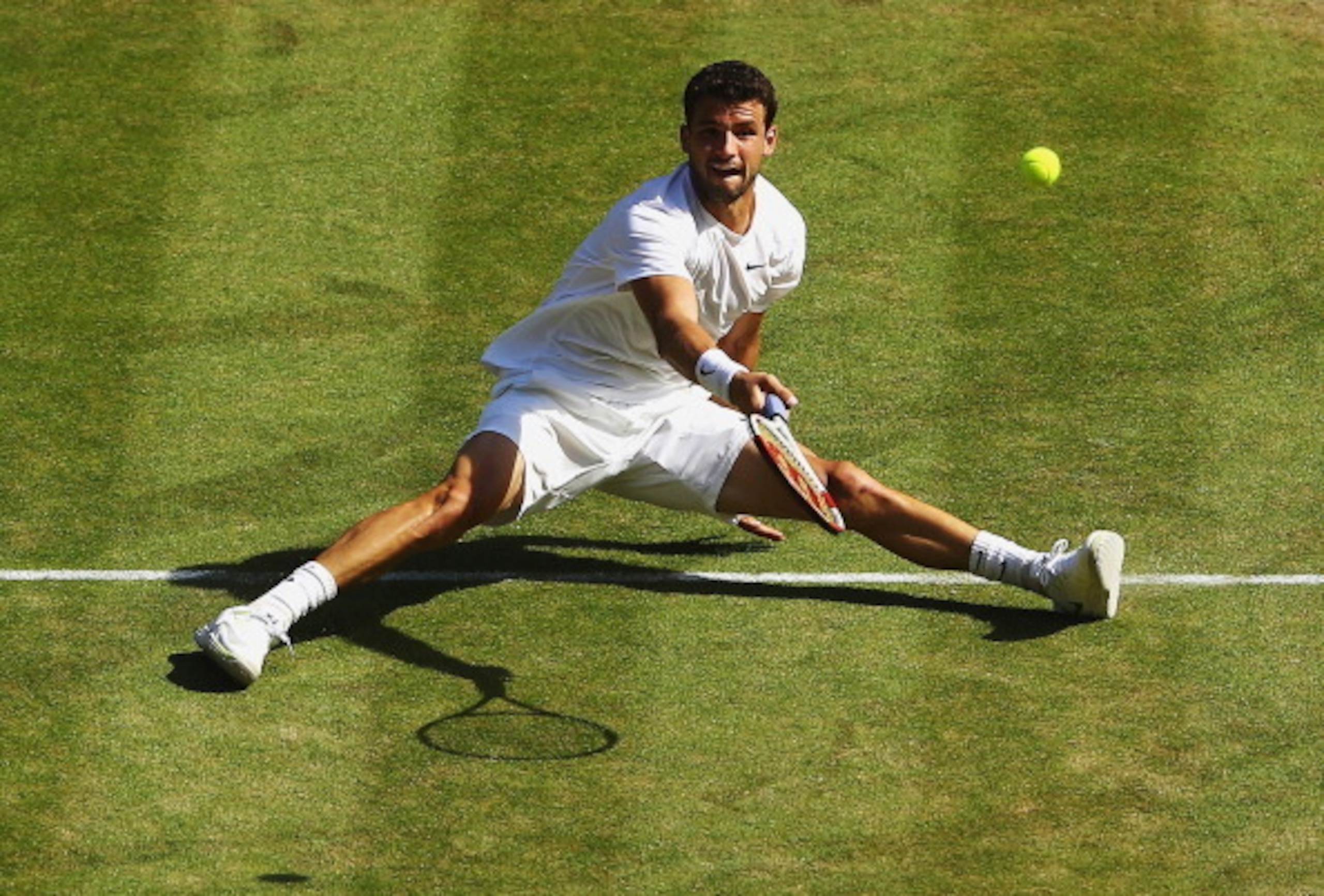 Grigor Dimitrov tries to slide his way to the ball during the Wimbledon semifinals.