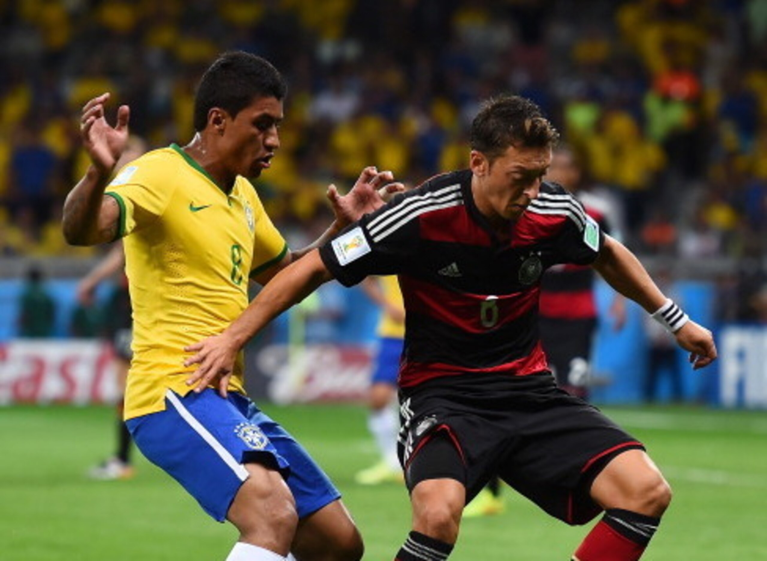 Paulinho squares up against Germany's Arsenal attacker Mesut Ozil during Brazil's embarrassing World Cup defeat to the eventual winners.
