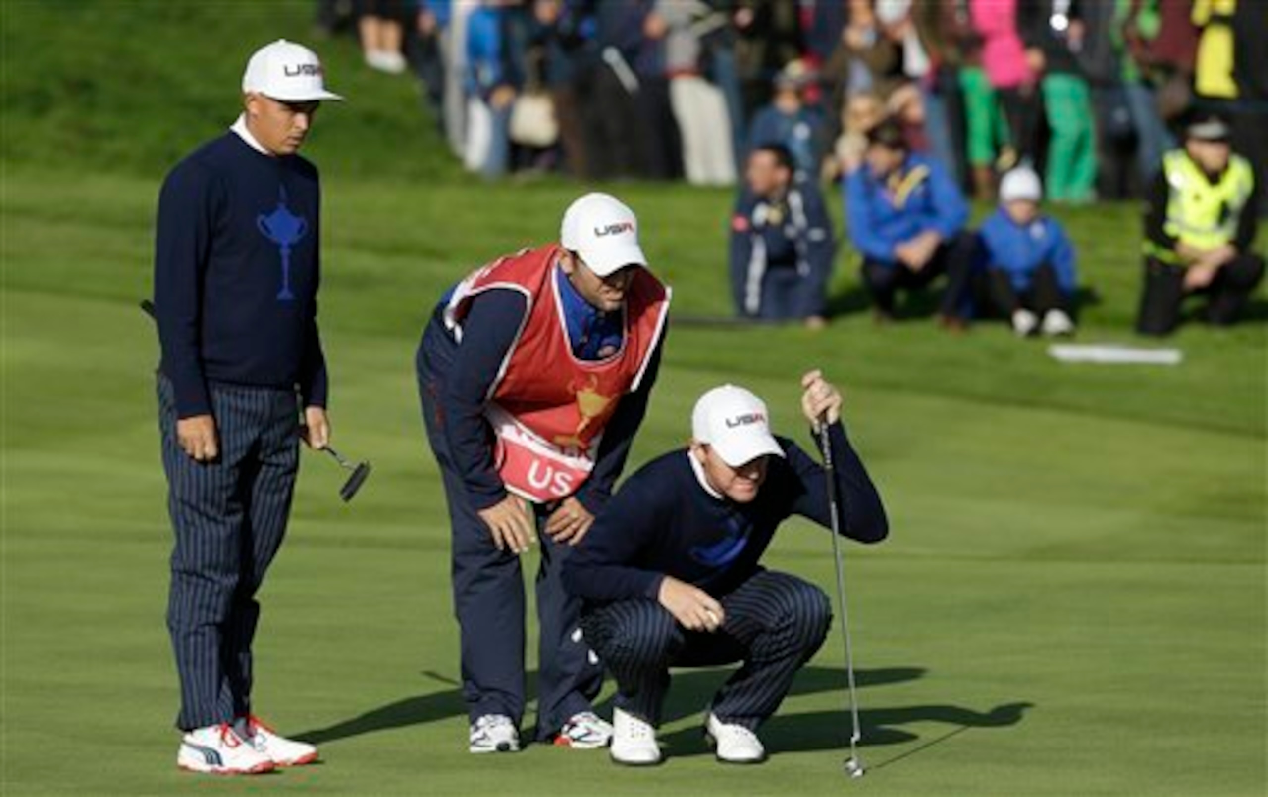Jimmy Walker, his caddie and Rickie Fowler size up a putt.