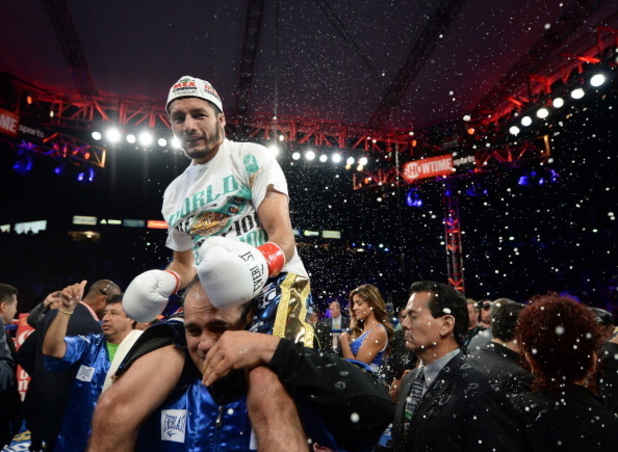 CARSON, CA - AUGUST 24:  Jhonny Gonzalez ducks a thrown beer from the crowd as he celebrates his first round knockout of Abner Mares during the WBC Featherweight Title Fight at the StubHub Center on August 24, 2013 in Carson, California.  (Photo by Harry 