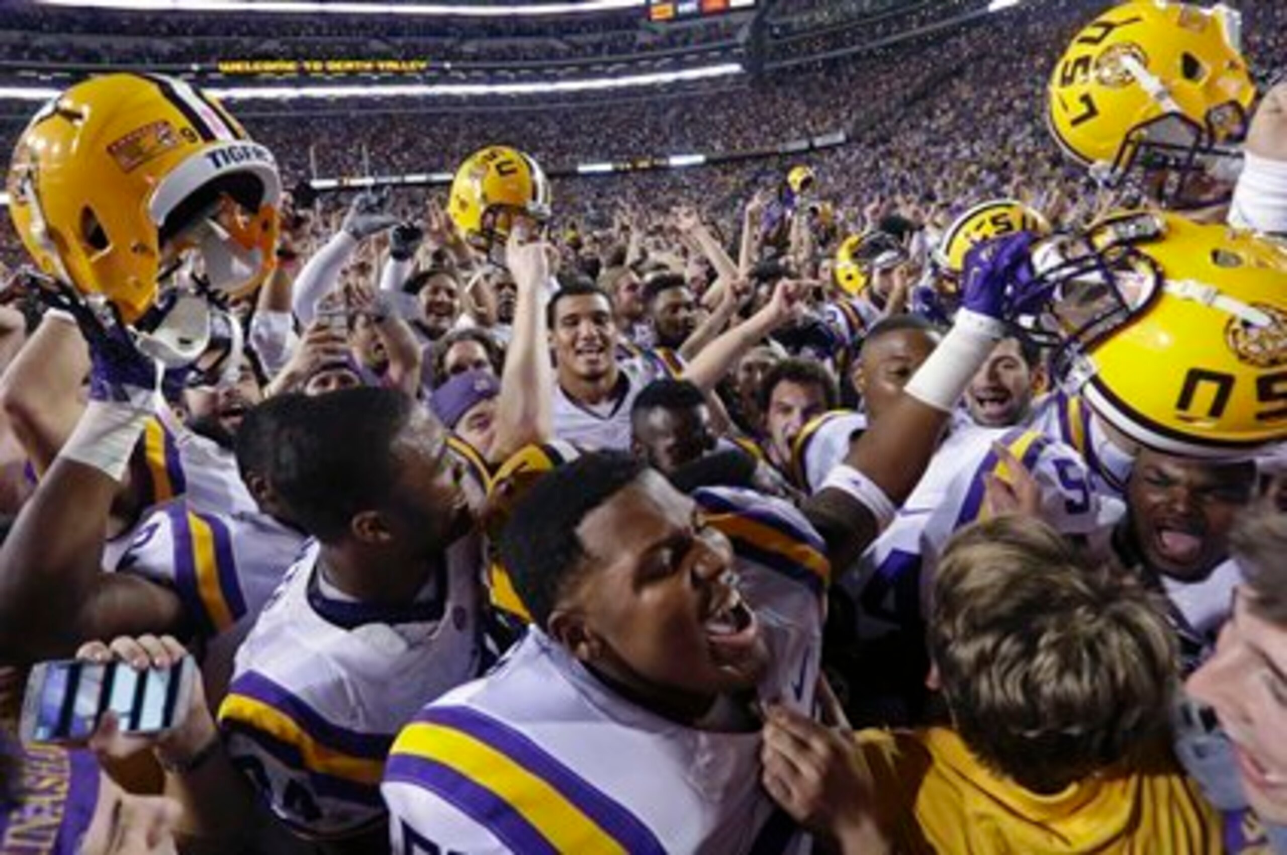 LSU's players celebrate win over Ole Miss as fans rush the field.