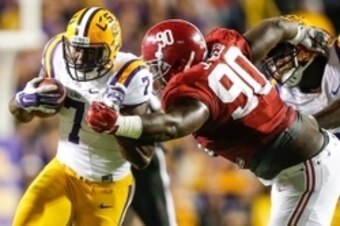 LSU running back Leonard Fournette (left) attempts to burst through the tackle of Alabama Jarran Reed.