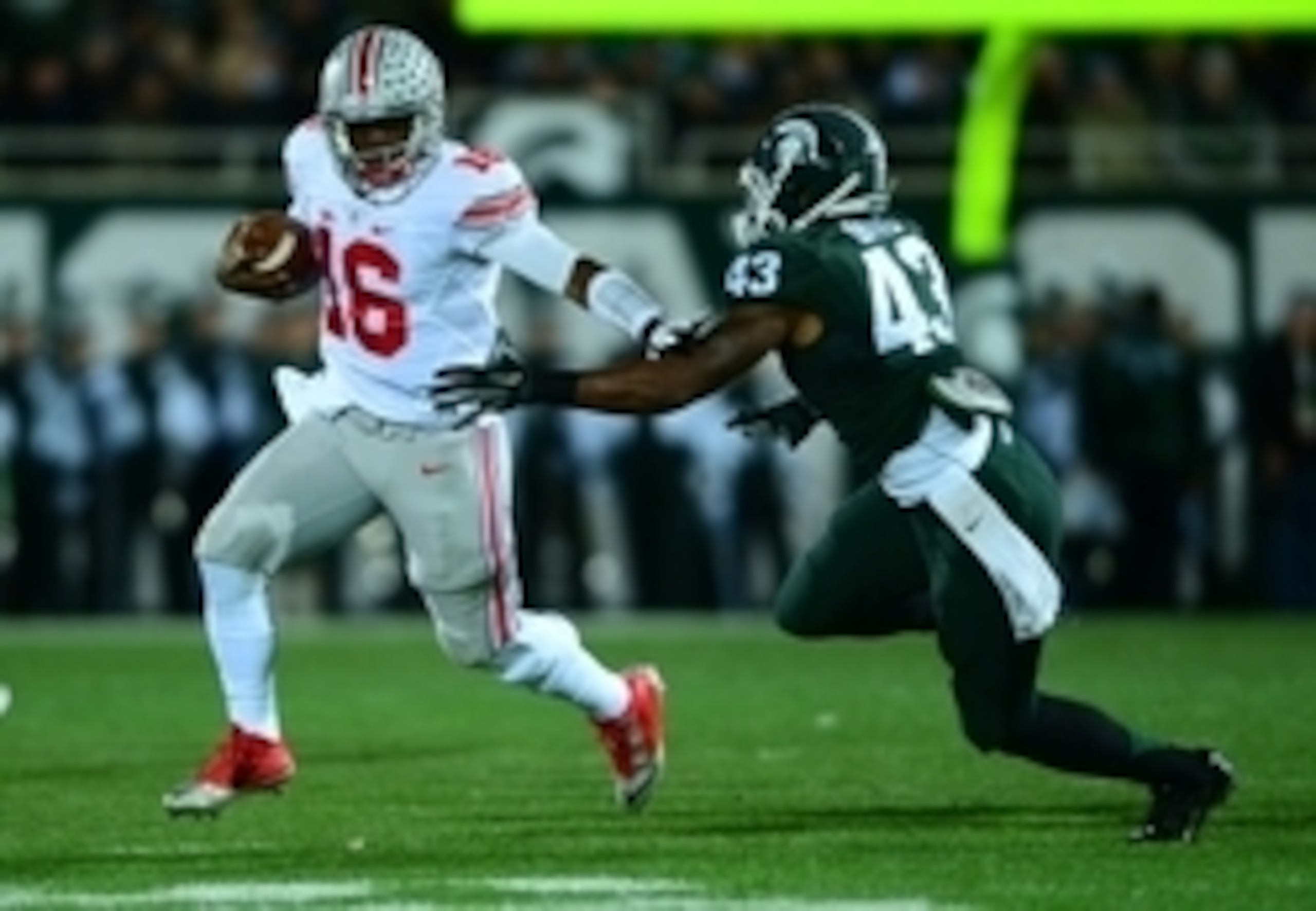 Nov 8, 2014; East Lansing, MI, USA; Ohio State Buckeyes quarterback J.T. Barrett (16) runs the ball away from Michigan State Spartans linebacker Ed Davis (43) during the first quarter at Spartan Stadium. Mandatory Credit: Andrew Weber-USA TODAY Sports
