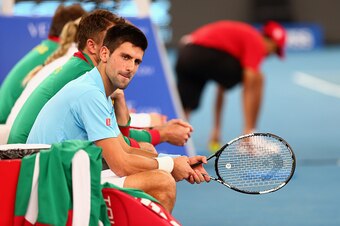 Novak Djokovic sits court-side with IPTL teammates.