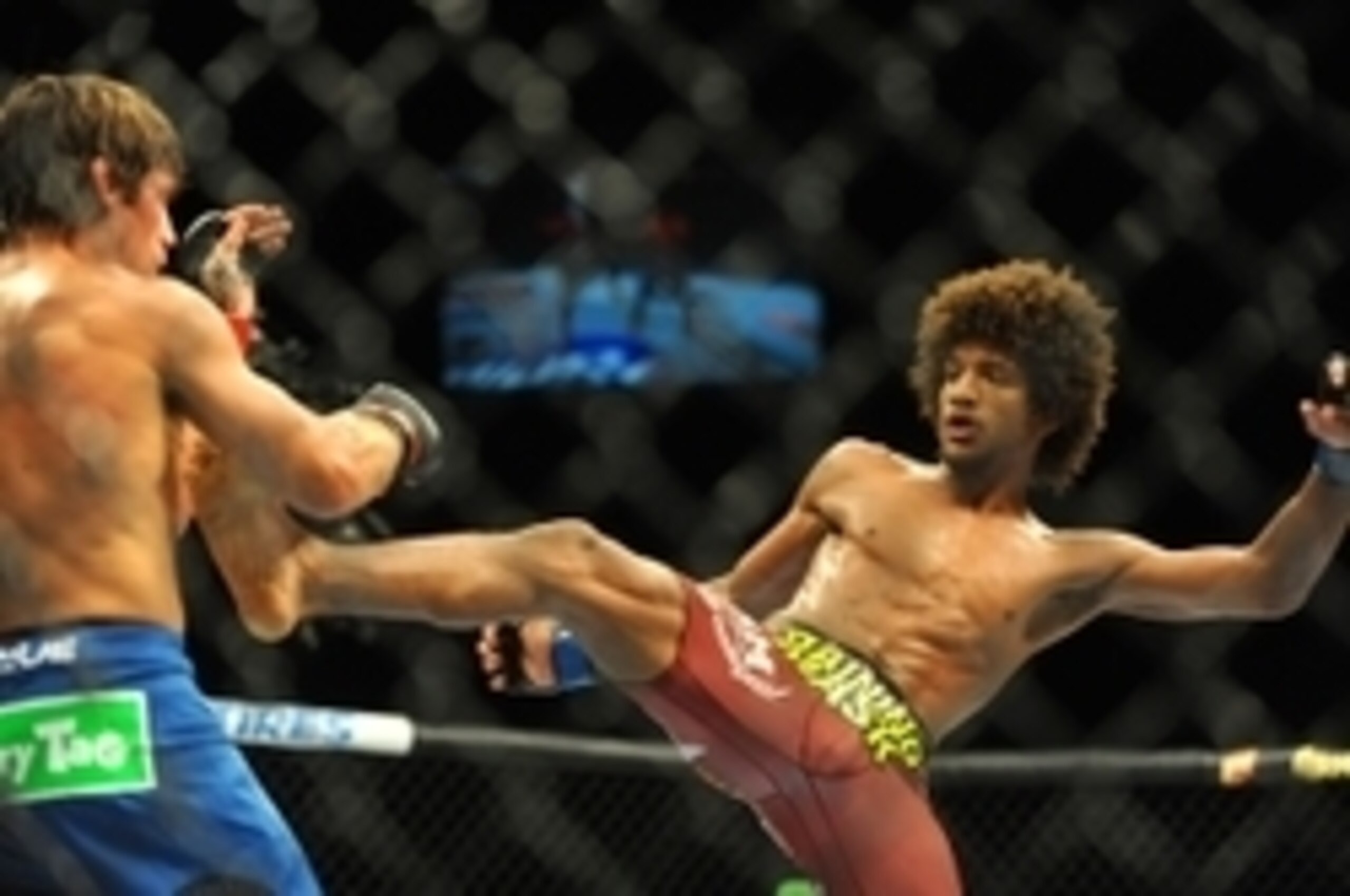 Jul 5, 2014; Las Vegas, NV, USA; Alex Caceres (blue gloves) lands a kick to Urijah Faber (red gloves) during a bantamweight fight at Mandalay Bay Events Center. Mandatory Credit: Stephen R. Sylvanie-USA TODAY Sports