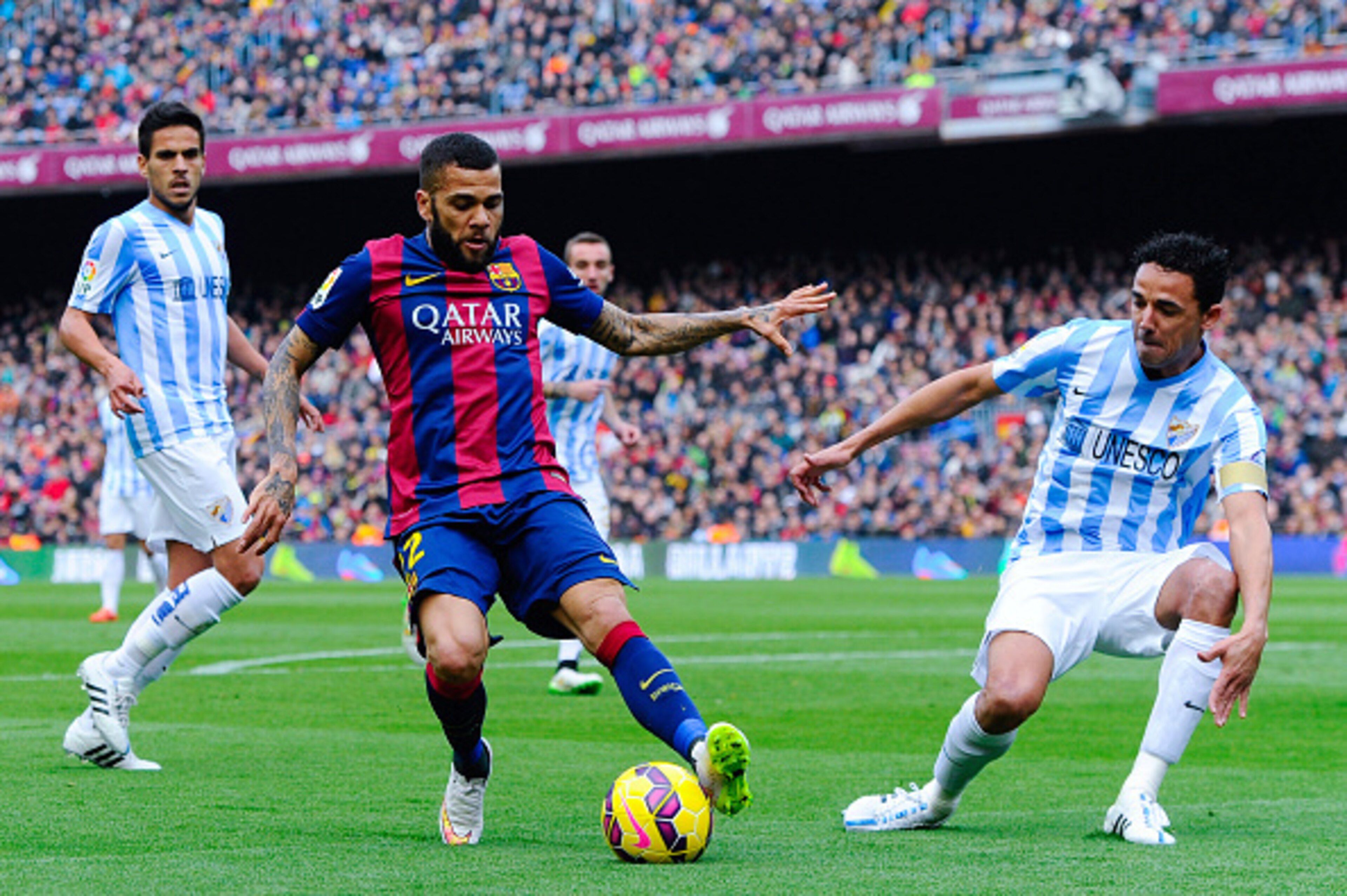 BARCELONA, SPAIN - FEBRUARY 21:  Dani Alves of FC Barcelona competes for the ball with Welligton Robson (R) and Miguel Torres of Malaga CF during the La Liga match between FC Barcelona and Malaga CF at Camp Nou on February 21, 2015 in Barcelona, Spain.  (