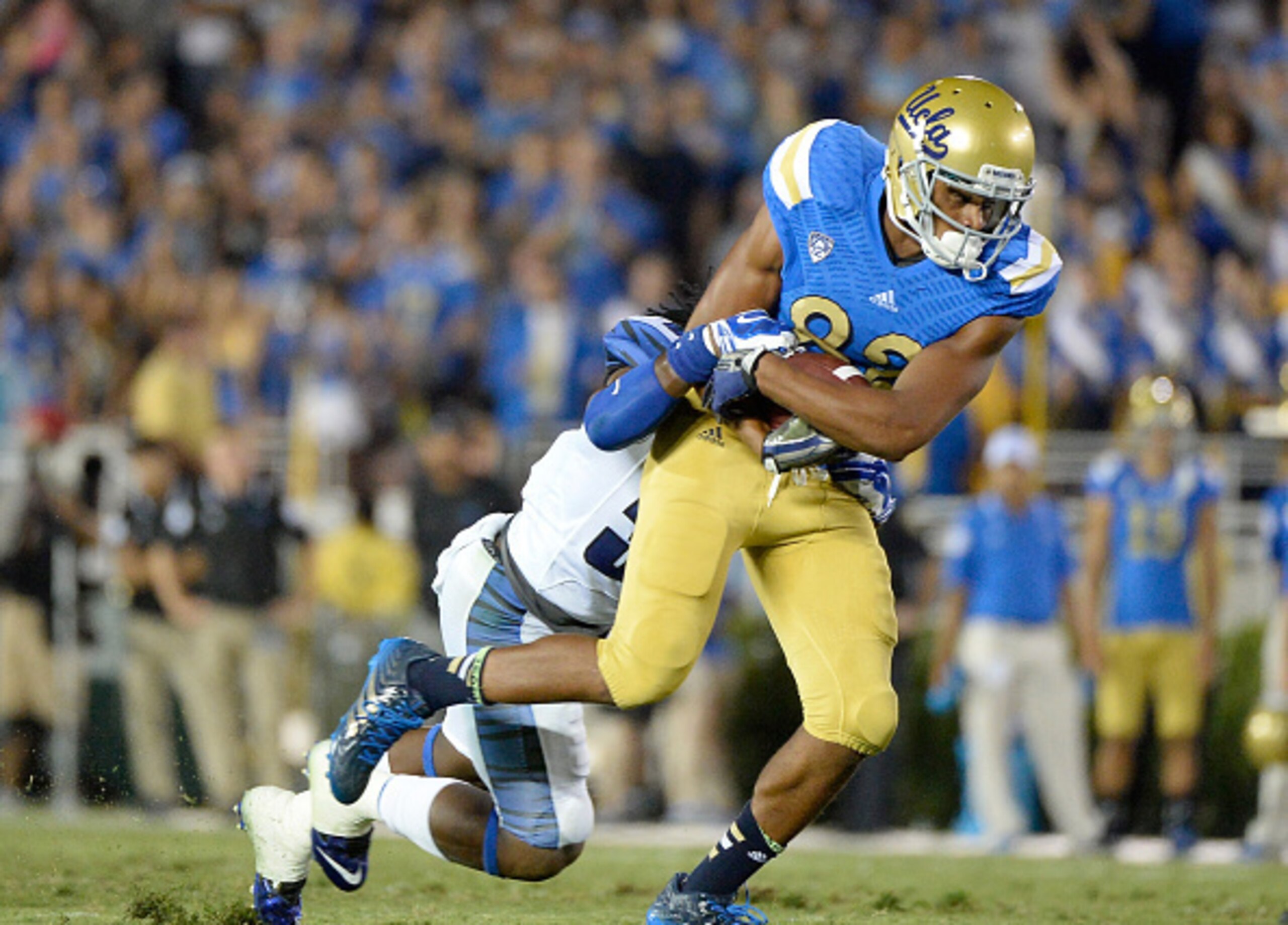 PASADENA, CA - SEPTEMBER 06:  Eldridge Massington #82 of the UCLA Bruins hangs on to the ball as Bakari Hollier #37 of the Memphis Tigers attempts a tackle from behind during the second half at Rose Bowl on September 6, 2014 in Pasadena, California.  (Pho