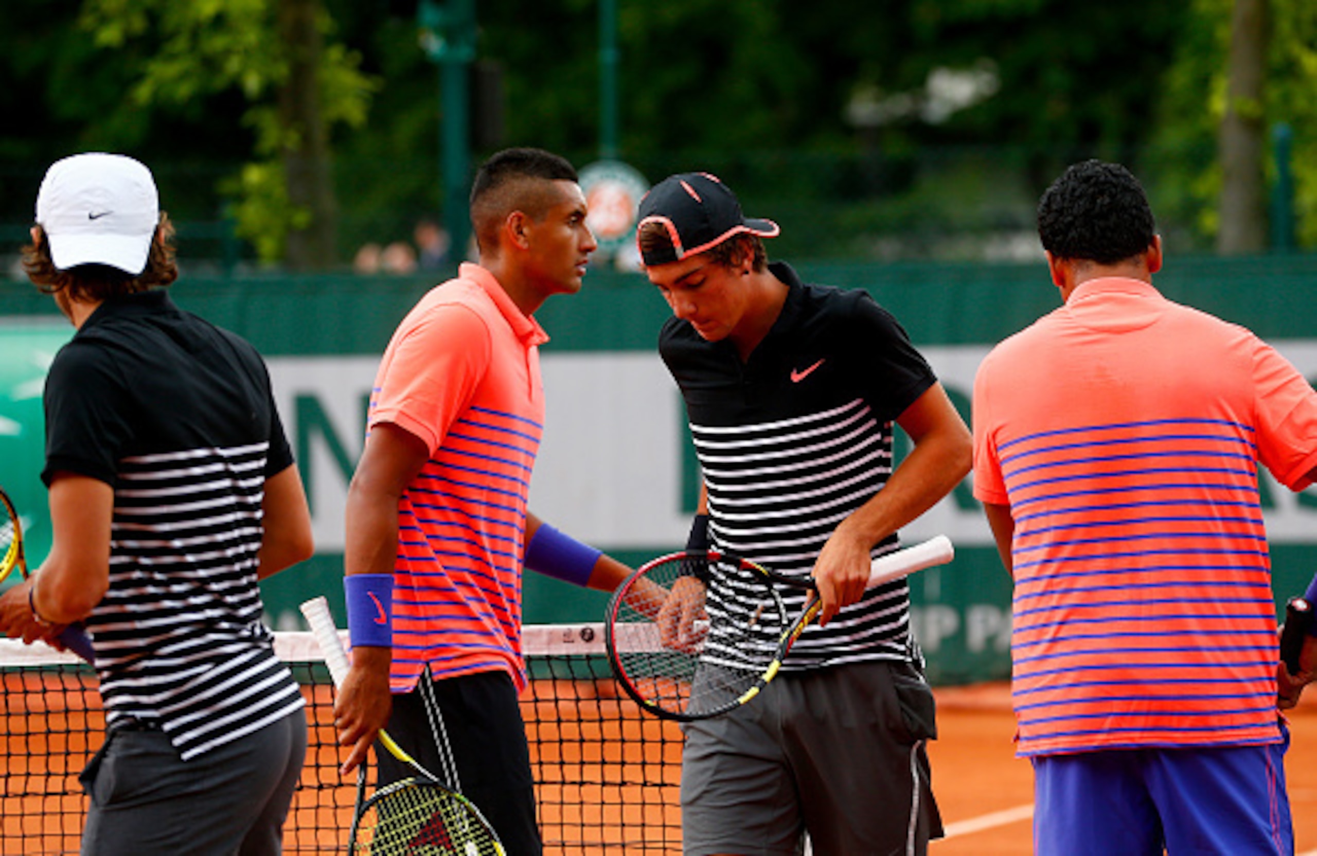 PARIS, FRANCE - MAY 26:  Thanasi Kokkinakis of Australia (2nd R) and Lucas Pouille of France (L) walk past Nick Kyrgios (2nd L) of Australia and Mahesh Bhupathi (R) of India as they change ends during their men's doubles match on day three of the 2015 Fre