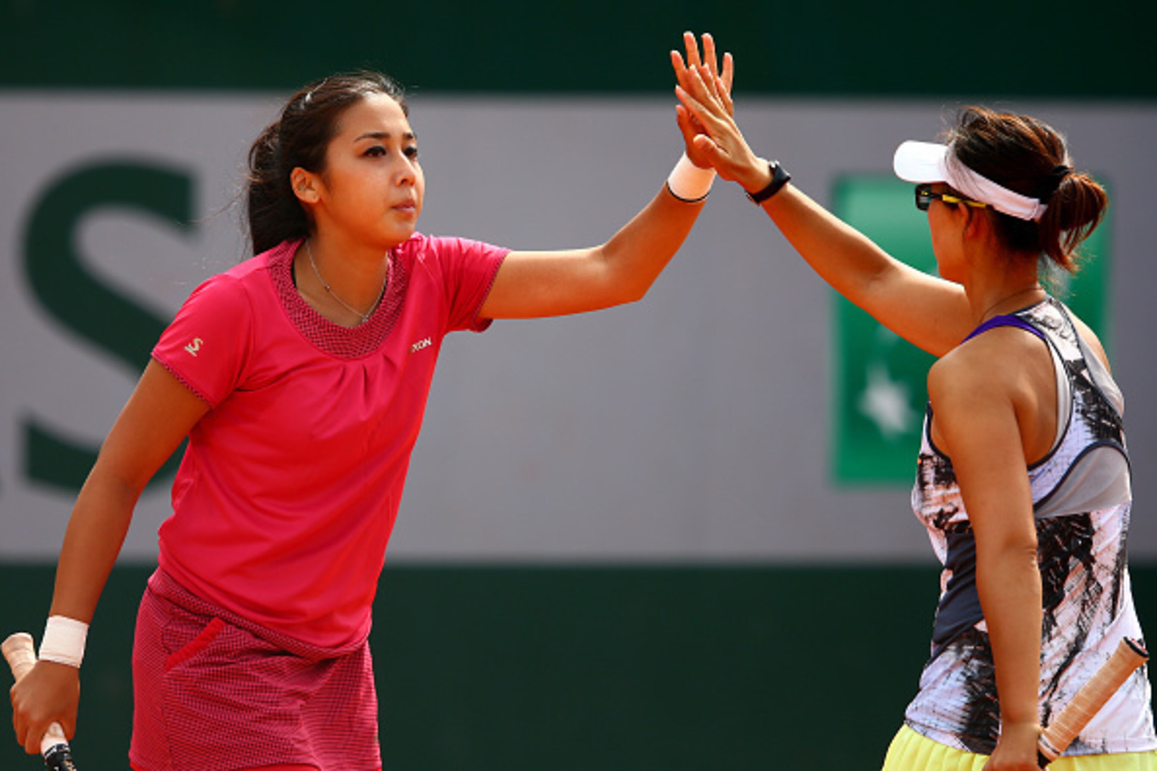 Zarina Diyas of Kazakhstan and Yi-Fan Xu of China high-five during a doubles match at the 2015 French Open.