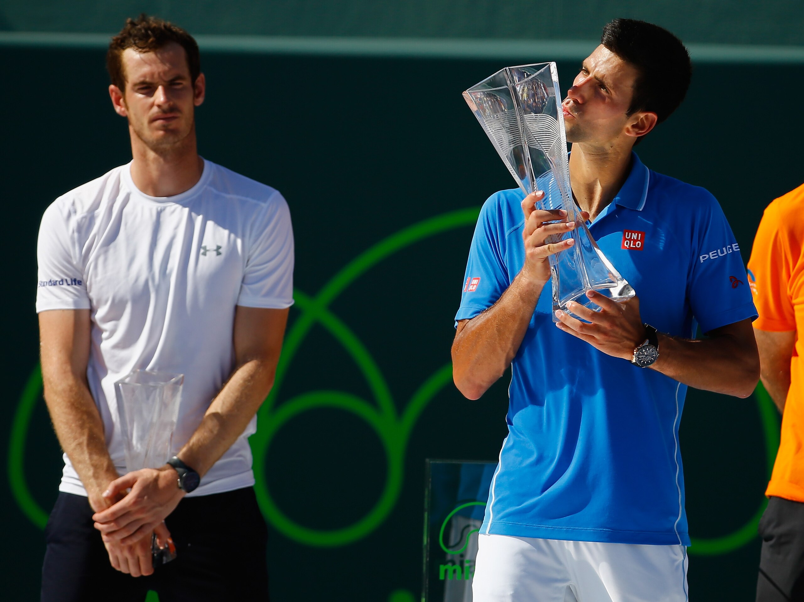 Andy Murray looks on as Novak Djokovic kisses the trophy after winning the 2015 Miami Open.