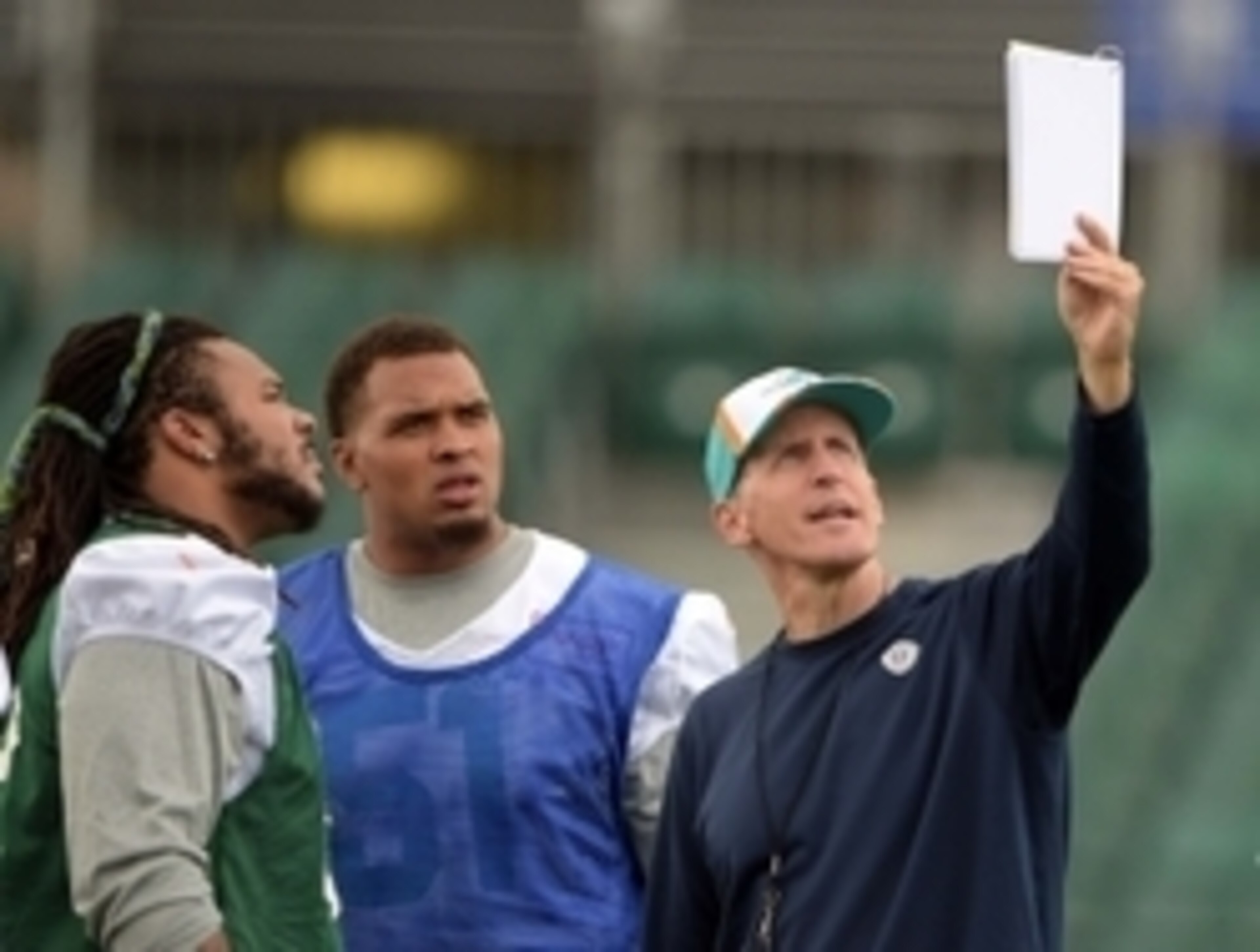 Sep 26, 2014; London, UNITED KINGDOM; Miami Dolphins coach Joe Philbin (right) holds a formation playbook to center Mike Poncey (51) and guard Billy Turner (left) at practice at Allianz Park in advance of the NFL International Series game between the Miam