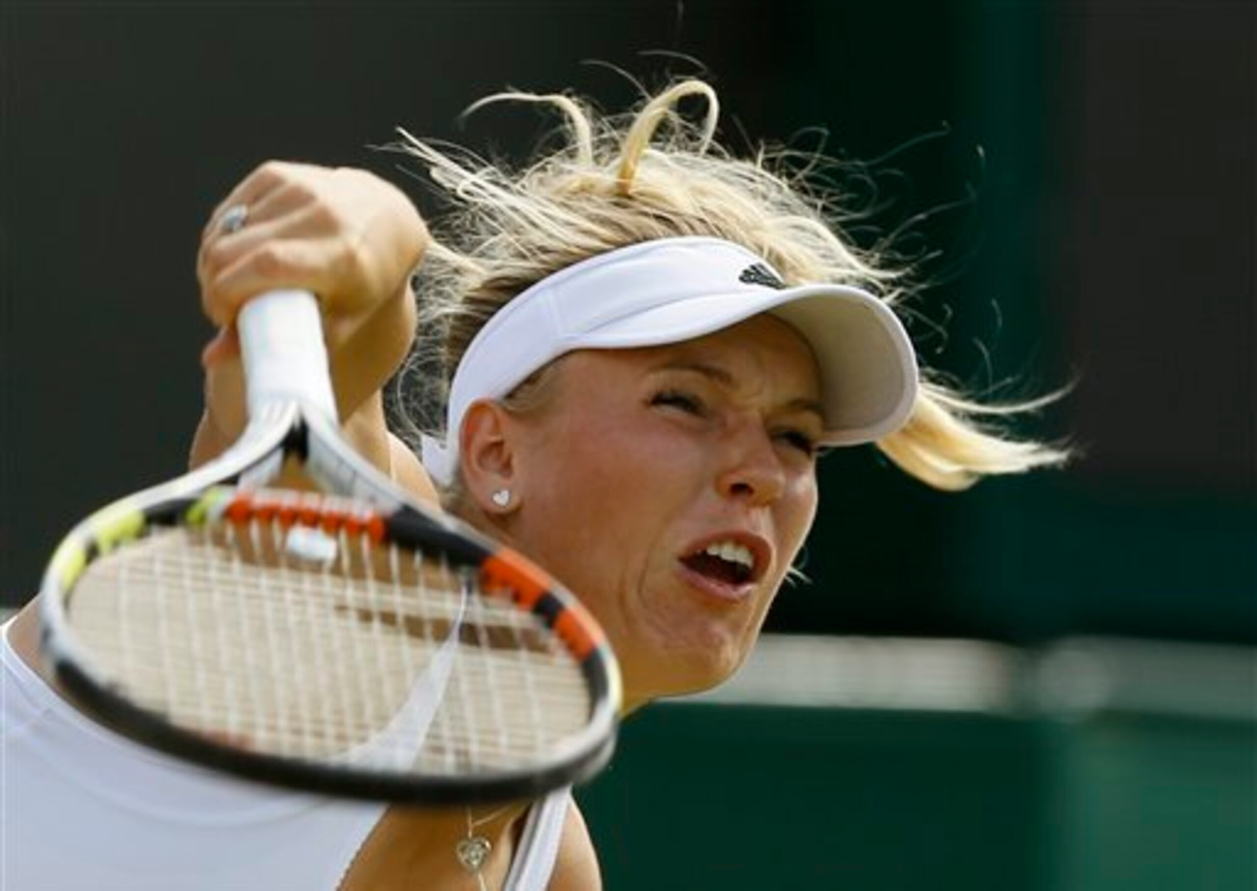 Caroline Wozniacki serves during a match against Garbine Muguruza at Wimbledon.