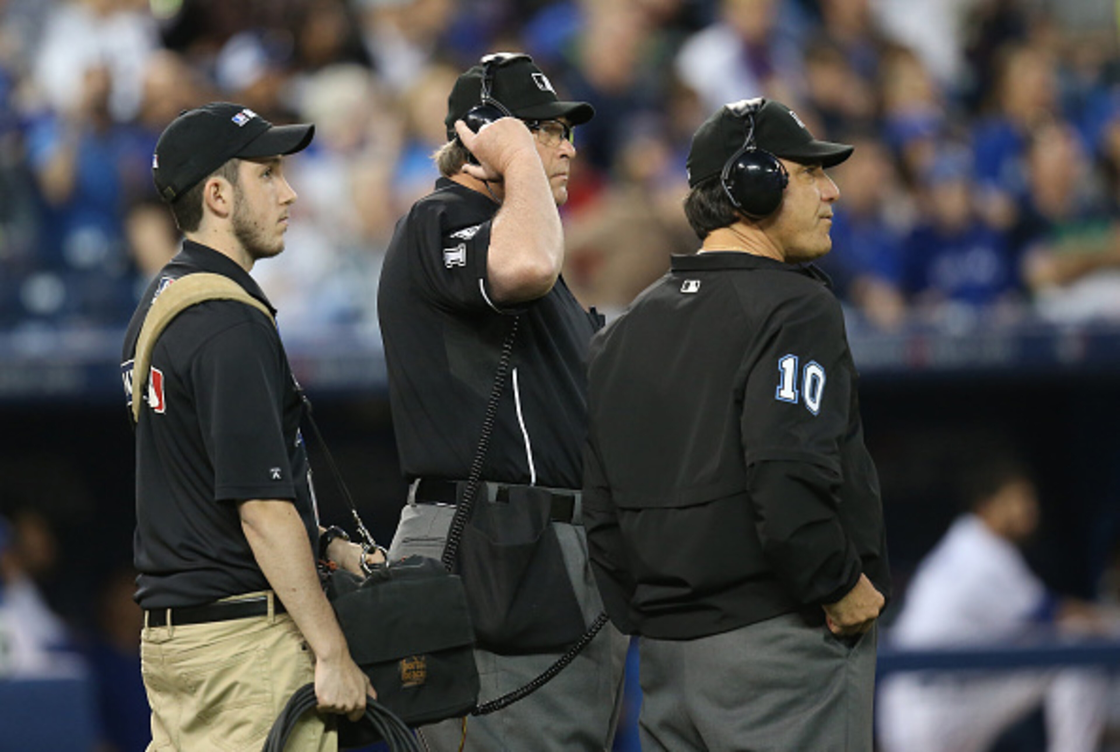 MLB umpires consult to review a call on the field.