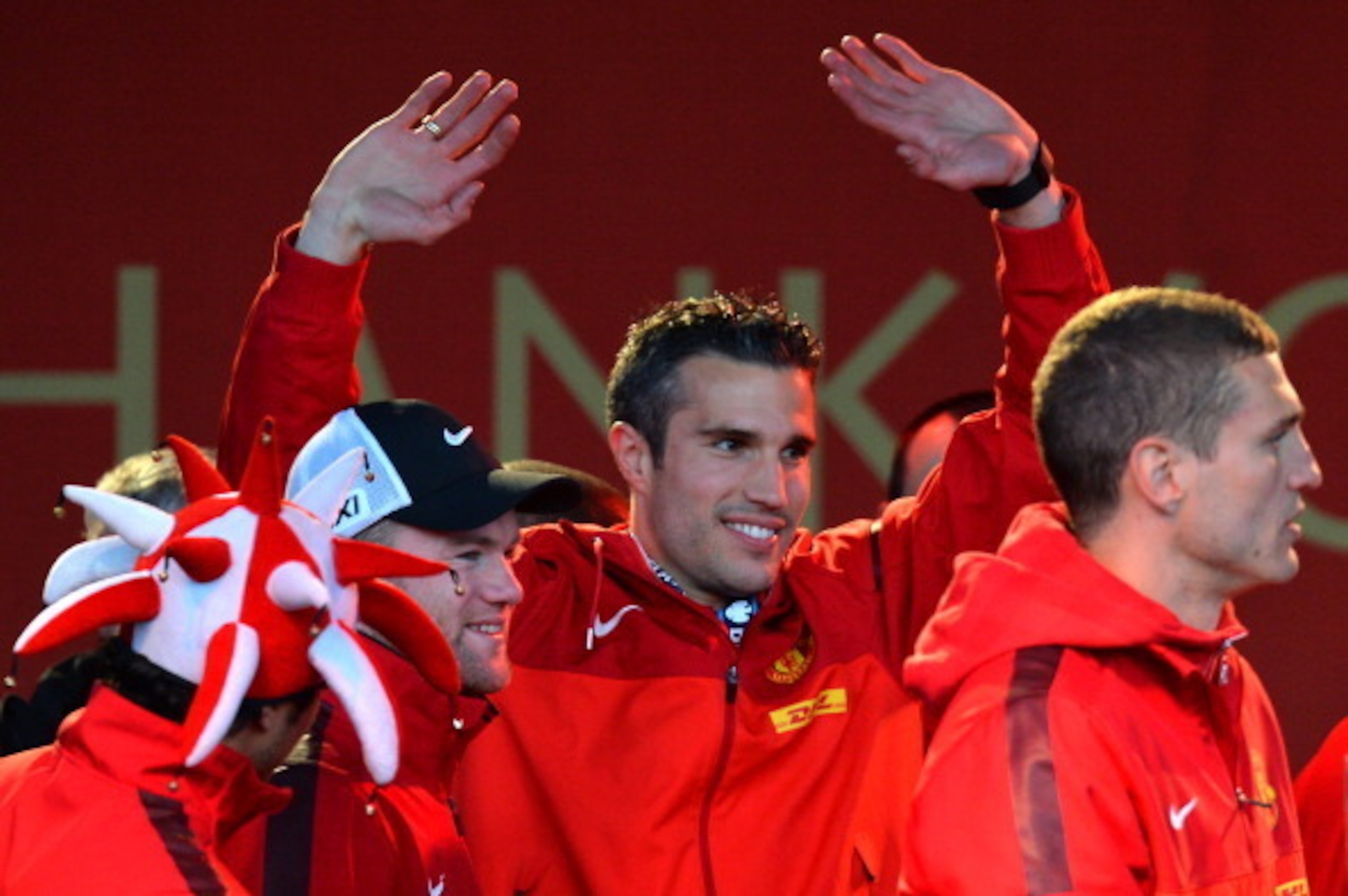 Manchester United's Dutch striker Robin van Persie (C) waves to the crowds as he celebrates with teammates on stage after winning the Premier League title for the 13th time, during the team's victory parade outside the town hall in Manchester, north west 