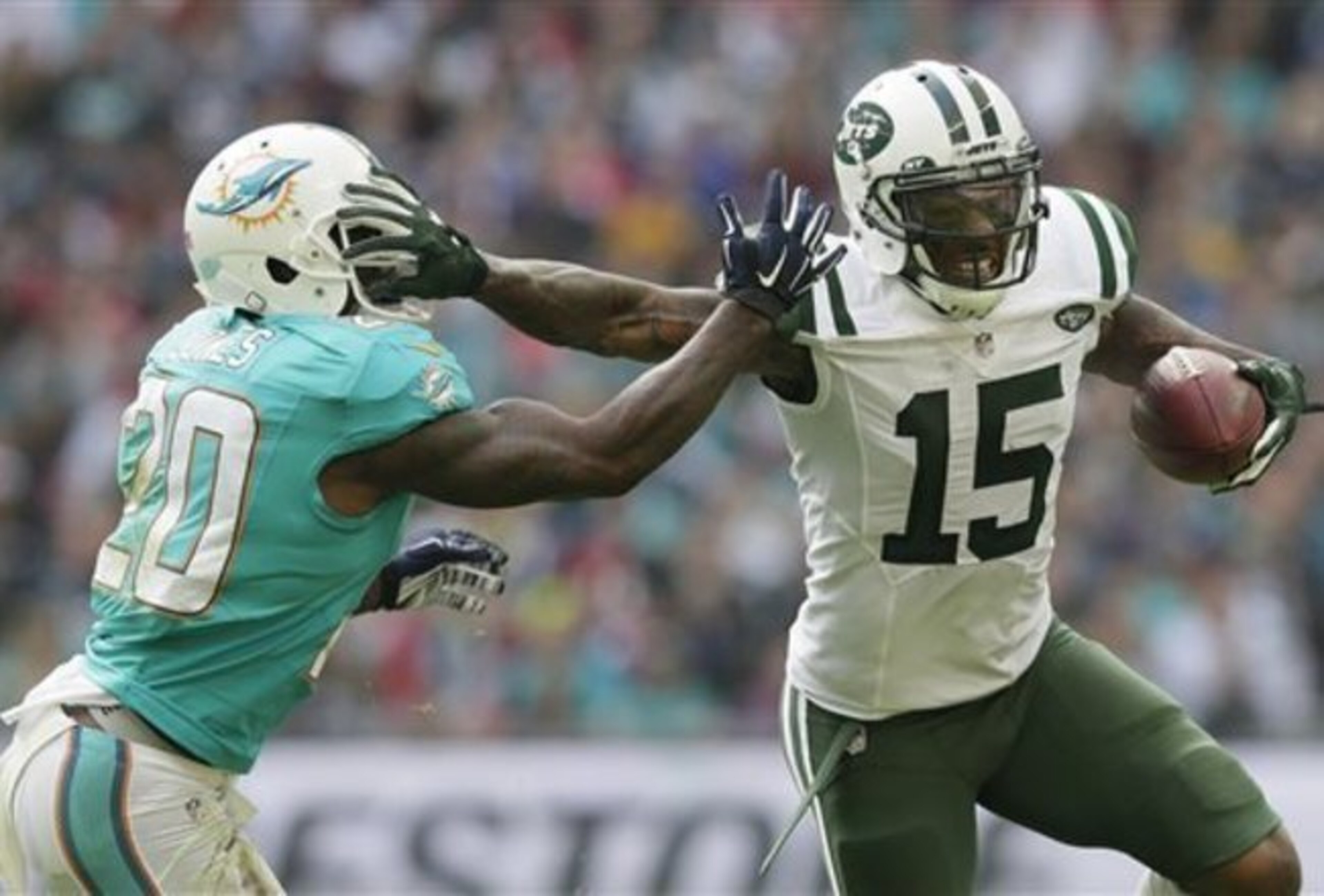 Jets receiver Brandon Marshall stiff-arms a Dolphins defender for extra yards after the catch.
