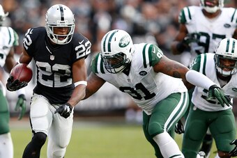 Raiders running back Taiwan Jones evading Jets defenders