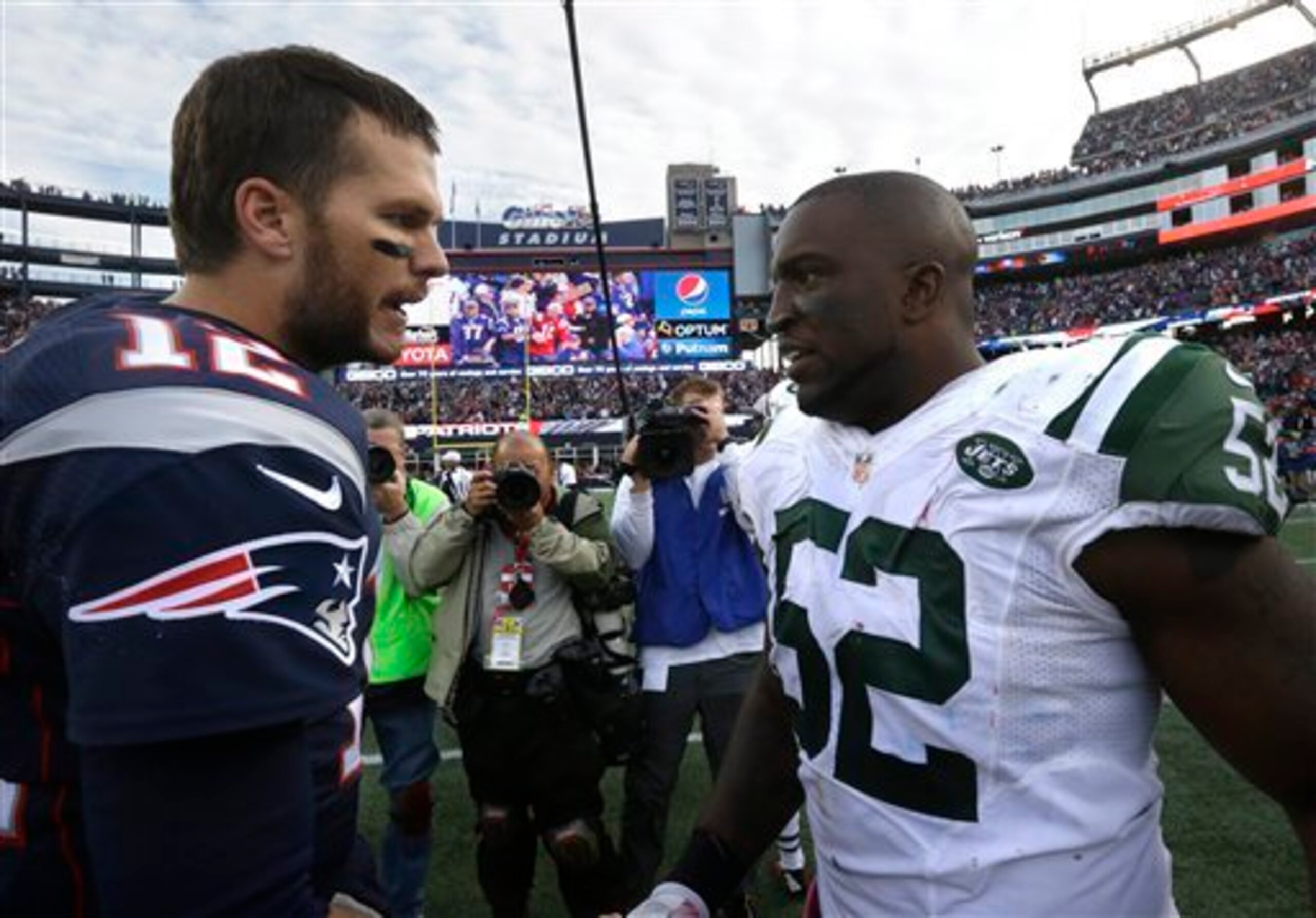 David Harris (52) talks to Patriots quarterback Tom Brady (12).
