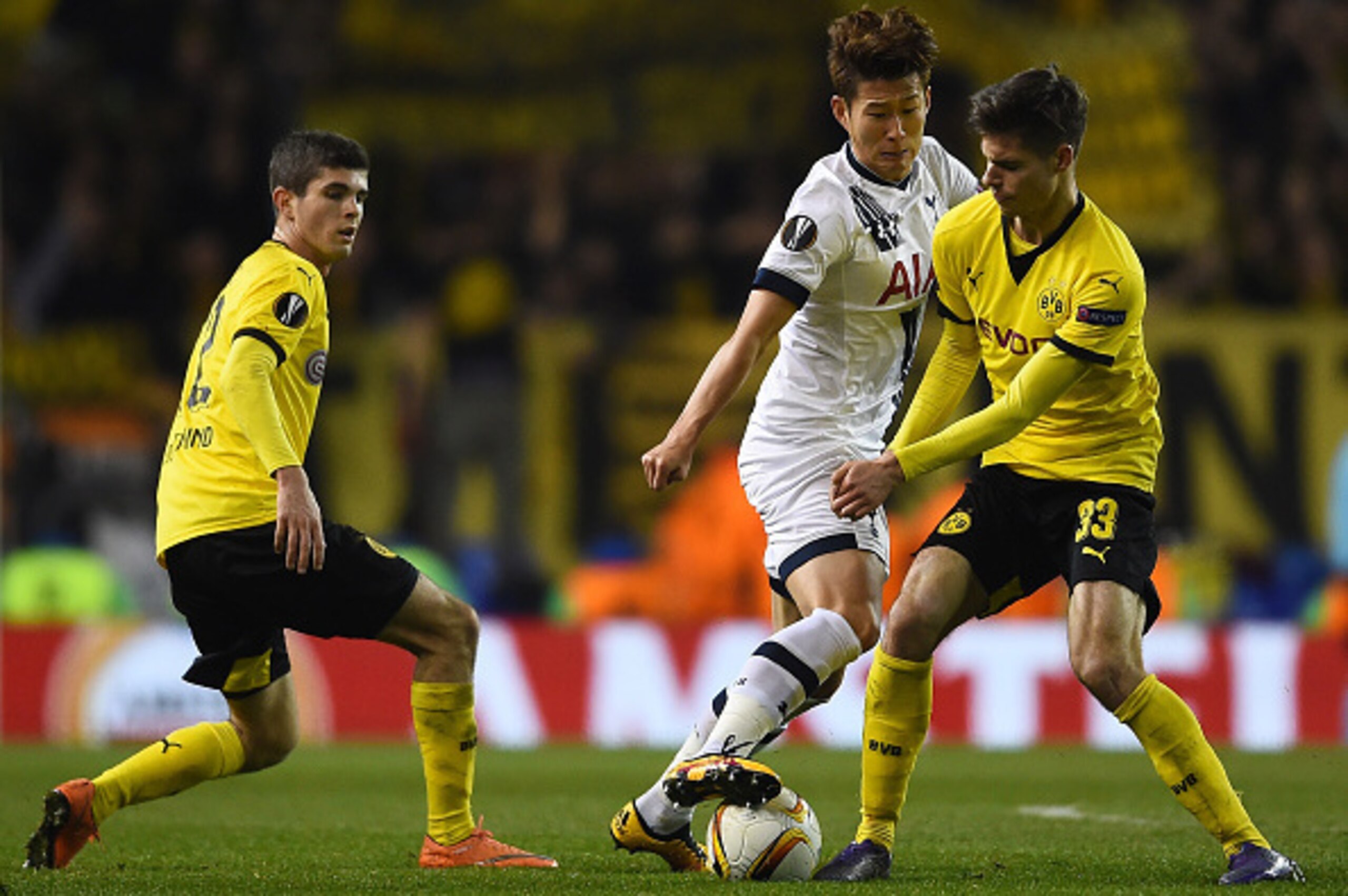 American Christian Pulisic watches on as Julian Weigl tries to take the ball off Heung-Min Son's feet.