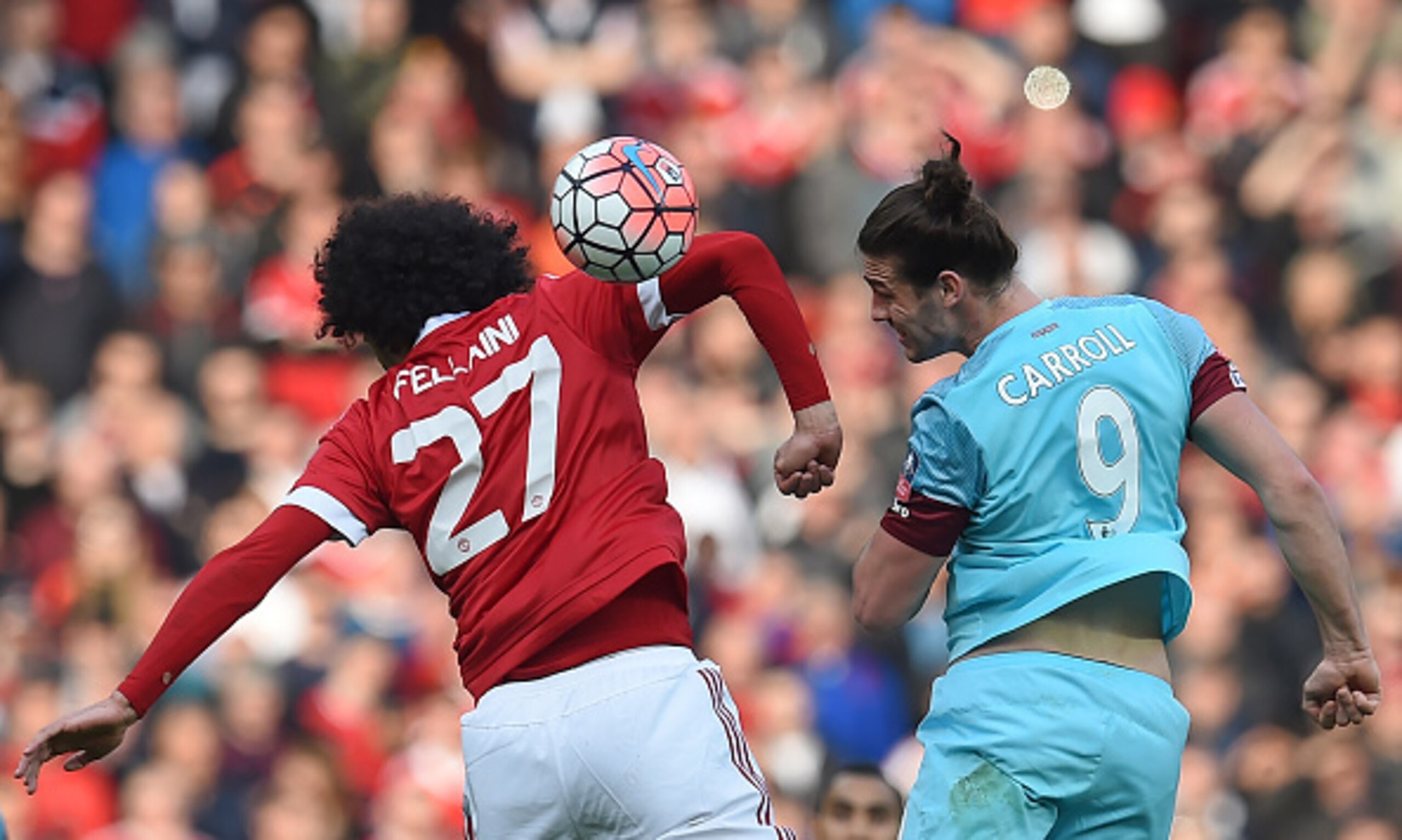 Fellaini and Carroll battle for the ball at Old Trafford.