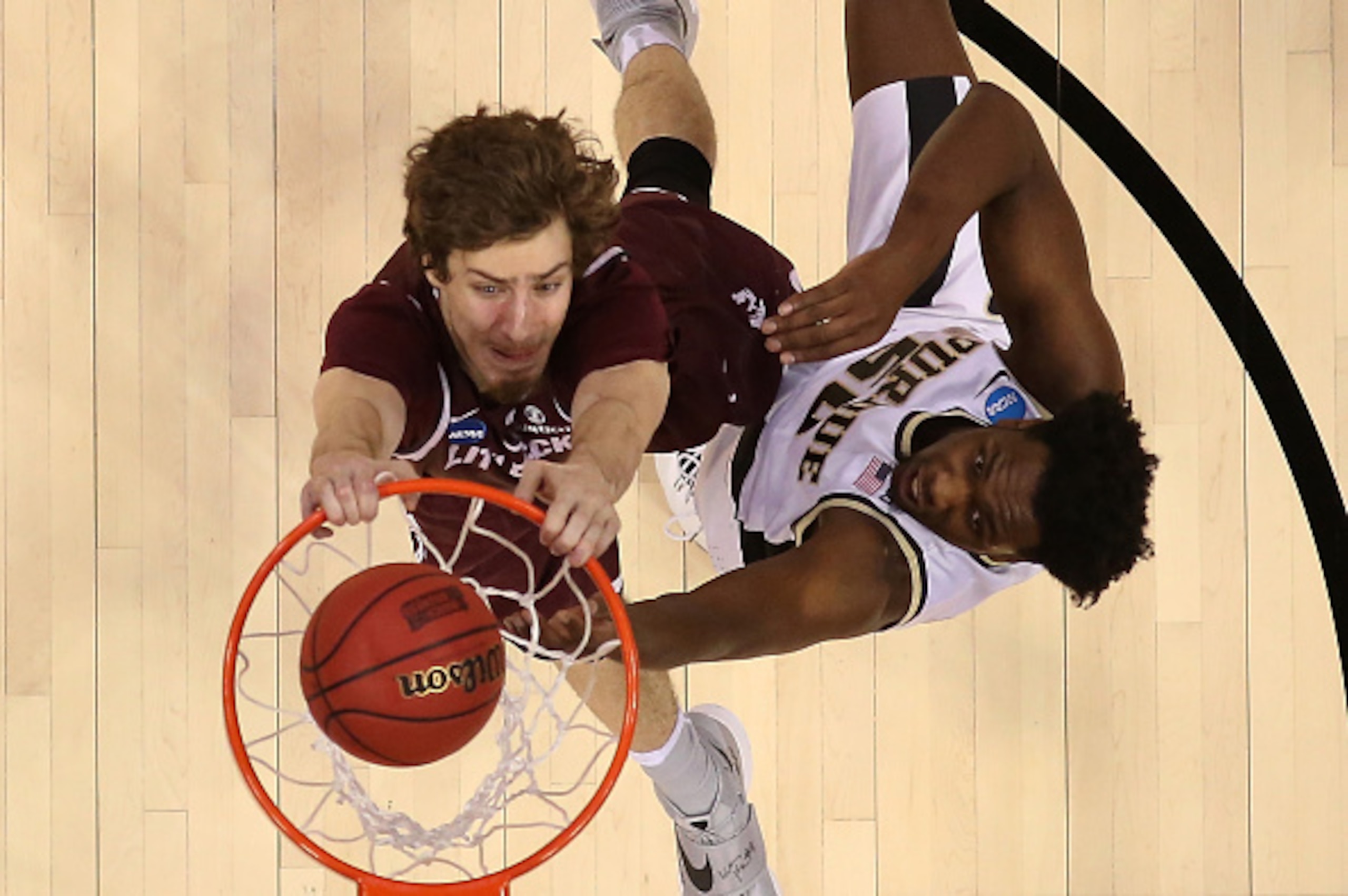 DENVER, CO - MARCH 17:  Lis Shoshi #12 of the Arkansas Little Rock Trojans dunks the ball over Caleb Swanigan #50 of the Purdue Boilermakers during the first round of the 2016 NCAA Men's Basketball Tournament at the Pepsi Center on March 17, 2016 in Denve