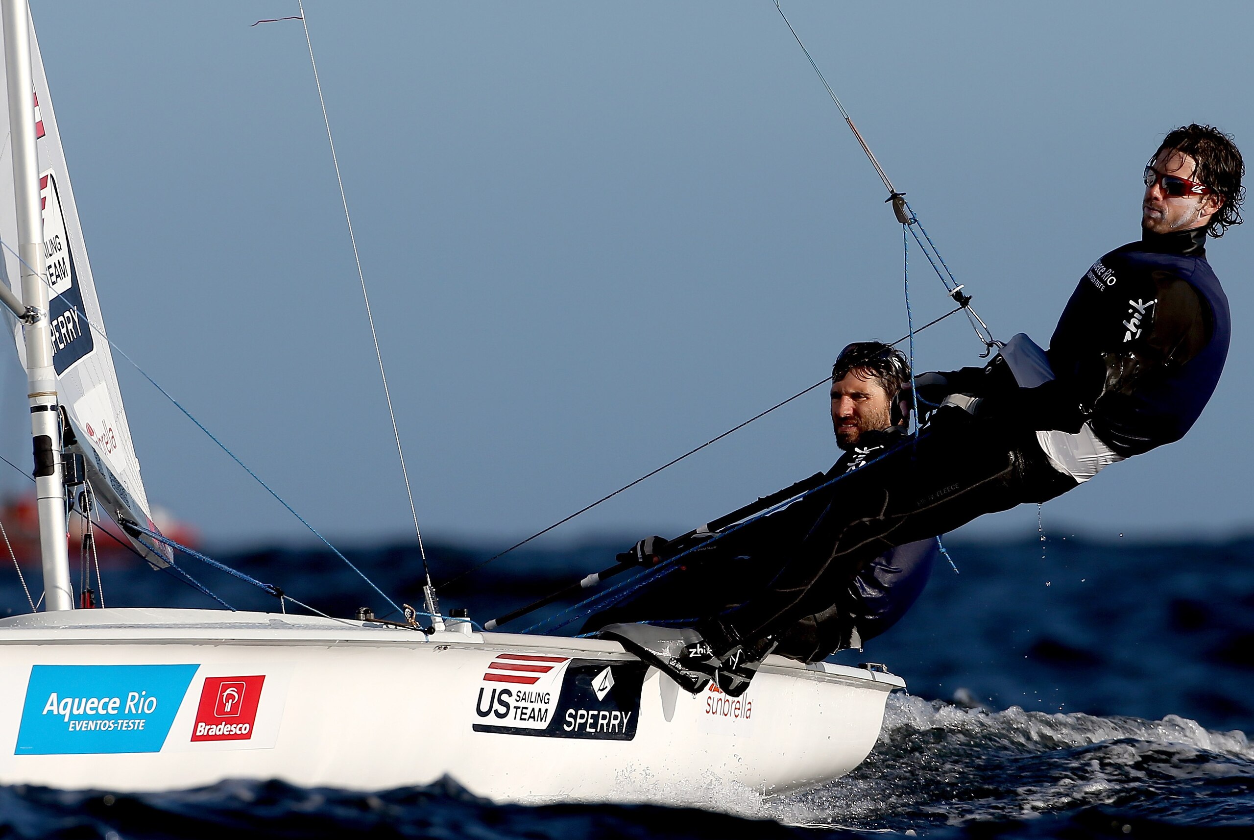 Stuart McNay has the 470 helm, while David Hughes dangles over the water.
