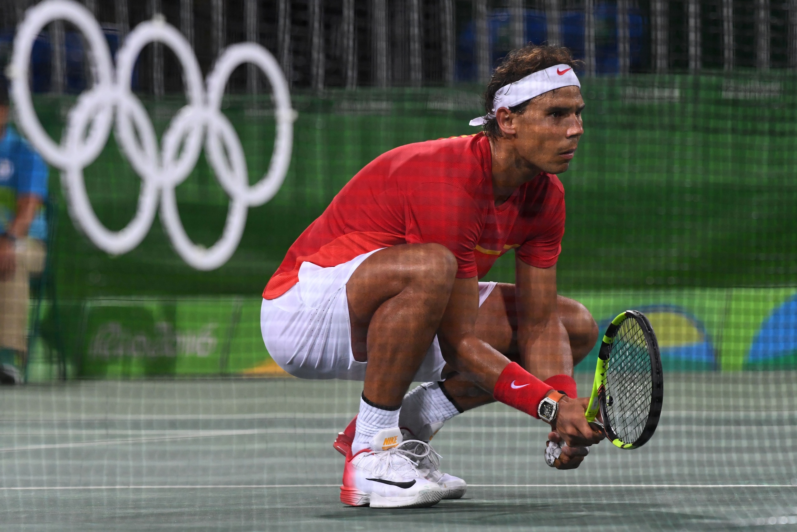 Rafael Nadal kneels just beyond the net in his doubles match at the 2016 Olympic Games in Rio.