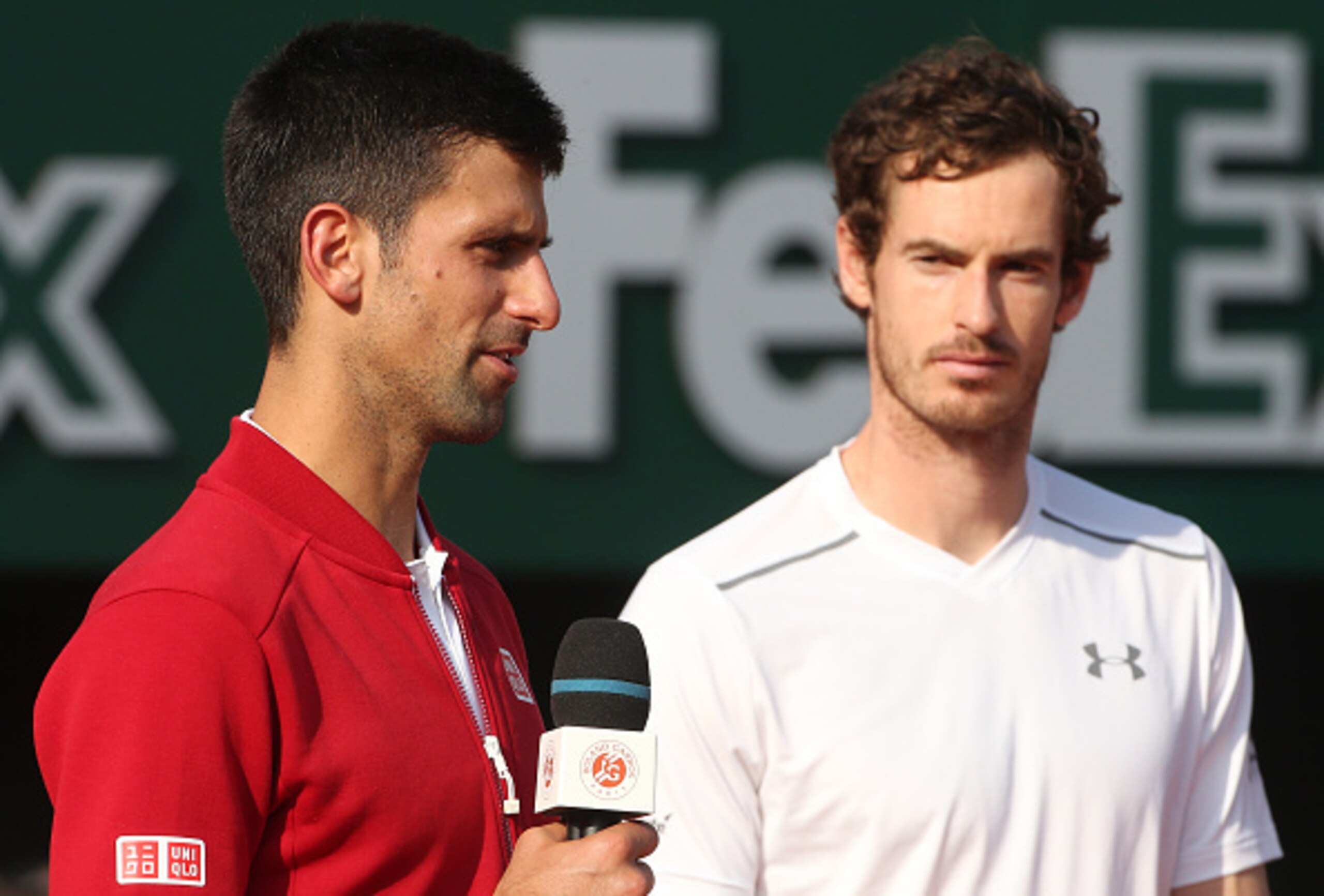 Novak Djokovic speaks to the French Open crowd as Andy Murray looks on.