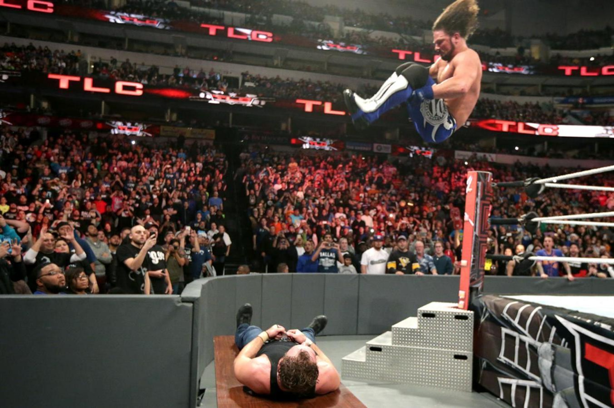 AJ Styles puts Dean Ambrose through a table with a 450 splash. AJ Styles puts Dean Ambrose through a table with a 450 splash.