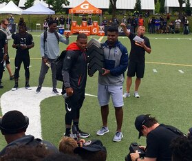 Former Ohio State star Ezekiel Elliott, right, presents J.K. Dobbins with the Nike Football Rating national championship trophy in July.
