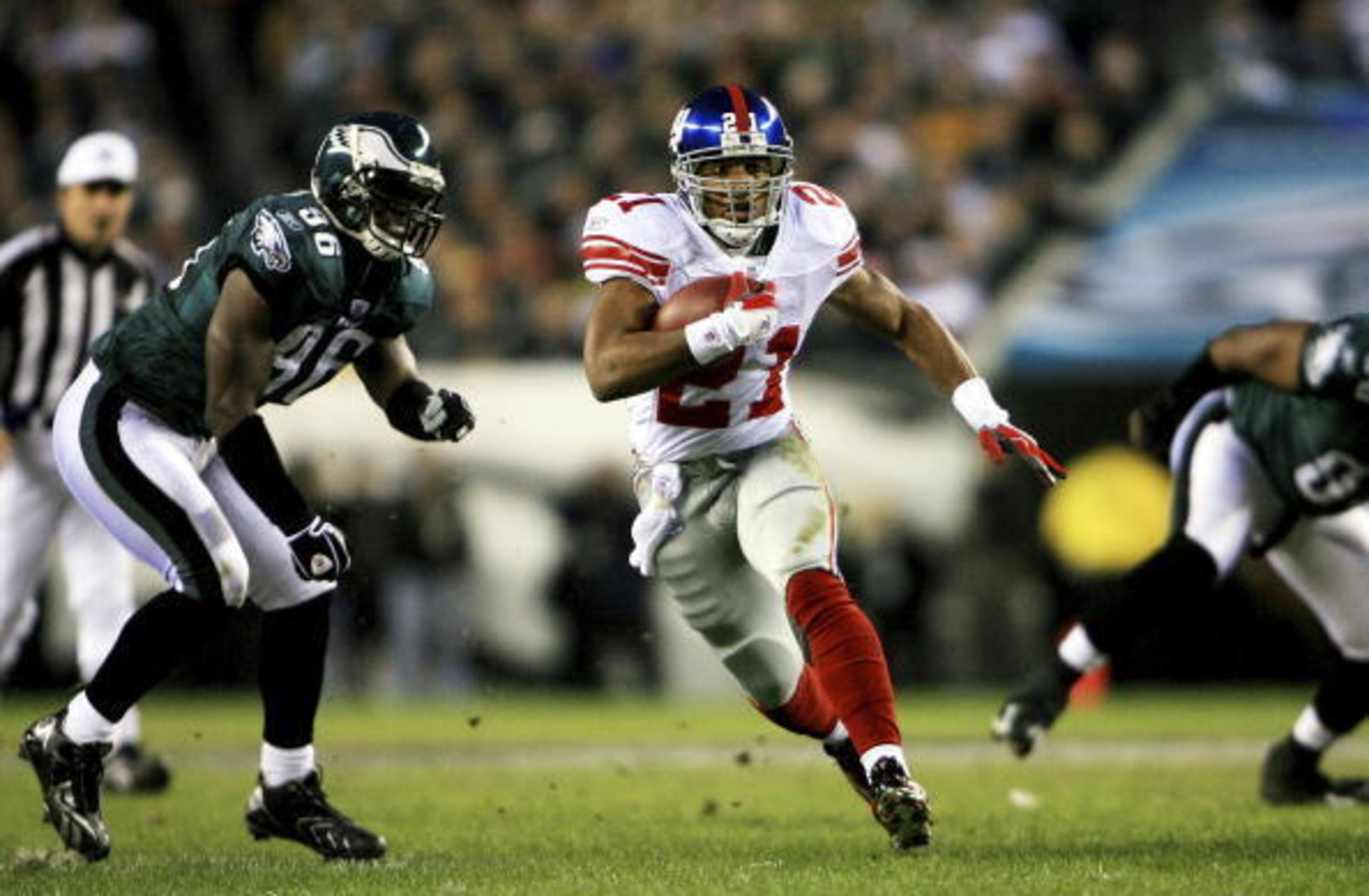 PHILADELPHIA - JANUARY 07:  Tiki Barber #21 of the New York Giants runs past Omar Gaither #96 of the Philadelphia Eagles during their NFC Wildcard Playoff game on January 7, 2007 at Lincoln Financial Field in Philadelphia, Pennsylvania.  (Photo by Chris M