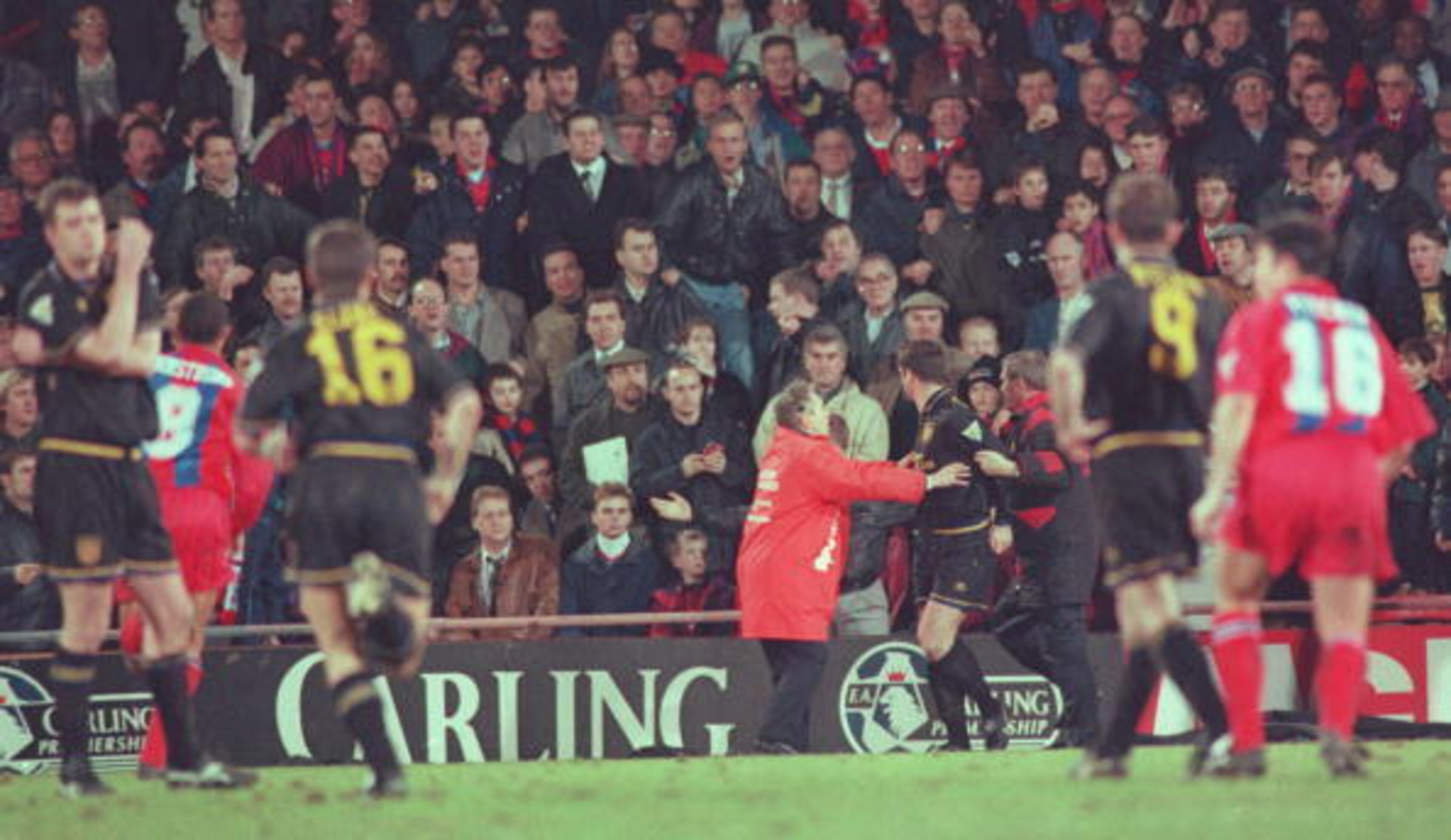 Cantona is held back by stewards at Selhurst Park.