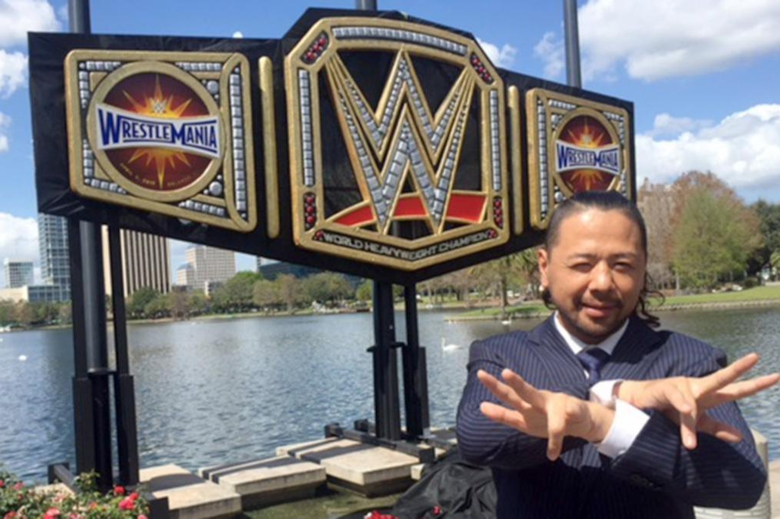 Shinsuke Nakamura posing with a giant WWE title belt.