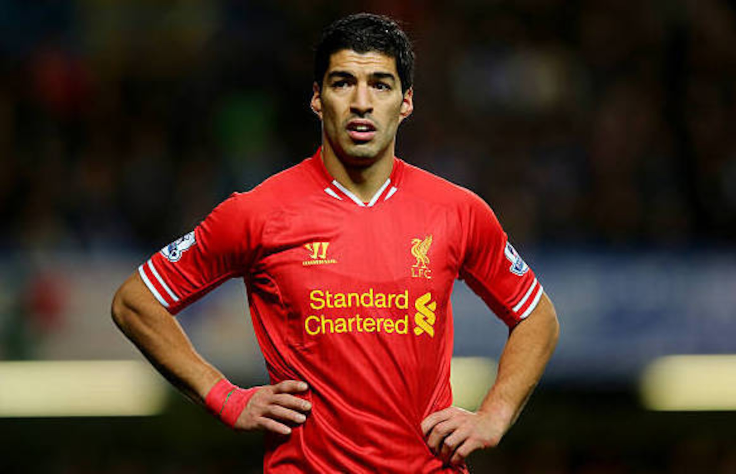 Luis Suarez models the shirt from the 2013/14 season, complete with matching red wrist bandage.