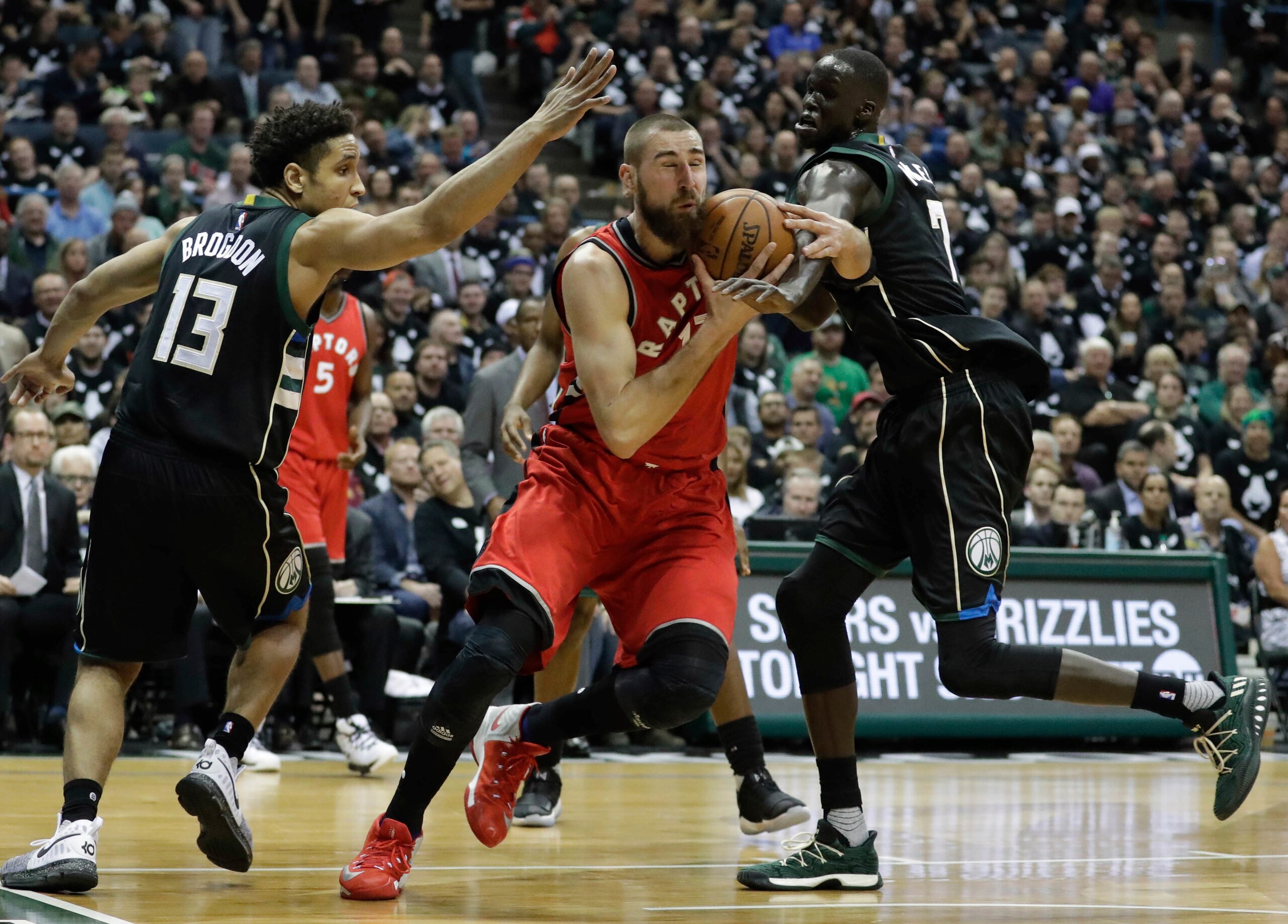 Milwaukee's Malcolm Brogon (13) and Thon Maker (7) defend Toronto's Jonas Valanciunas. Milwaukee's Malcolm Brogon (13) and Thon Maker (7) defend Toronto's Jonas Valanciunas.