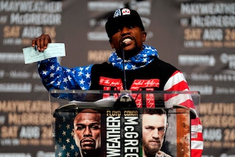 Floyd Mayweather holding up a nine-figure check on the first day of the World Tour.
