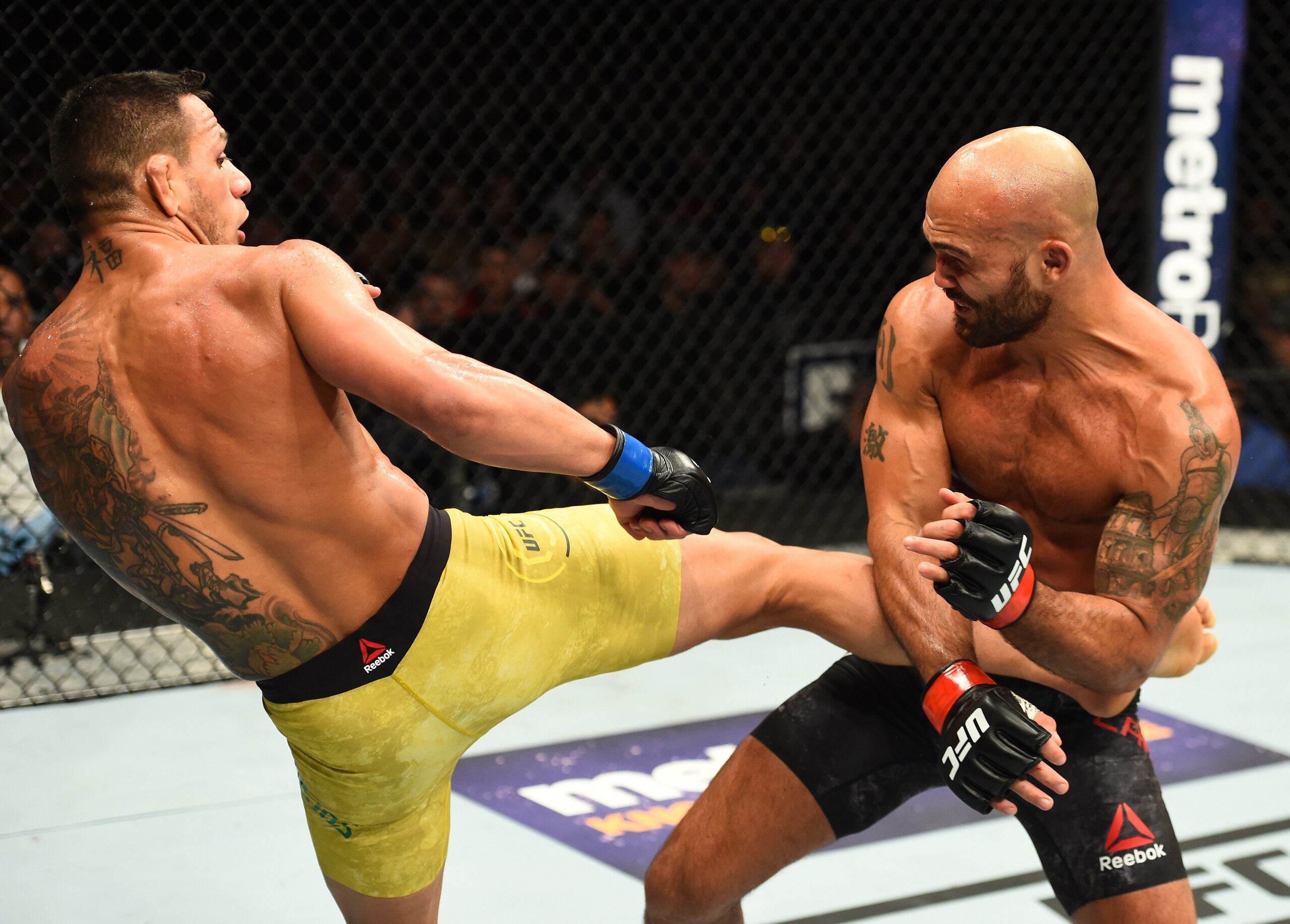 Rafael dos Anjos (left) kicks Robbie Lawler