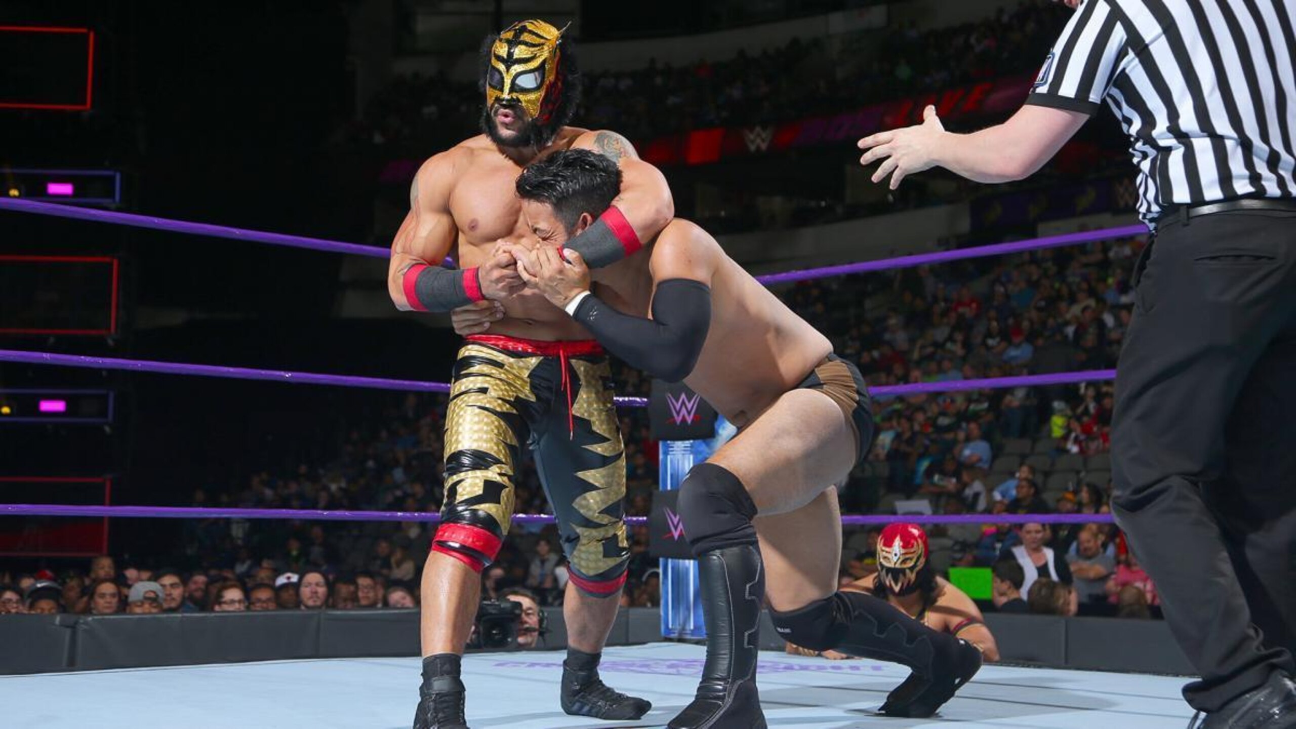 Lince Dorado holds Hideo Itami in a headlock. Lince Dorado holds Hideo Itami in a headlock.