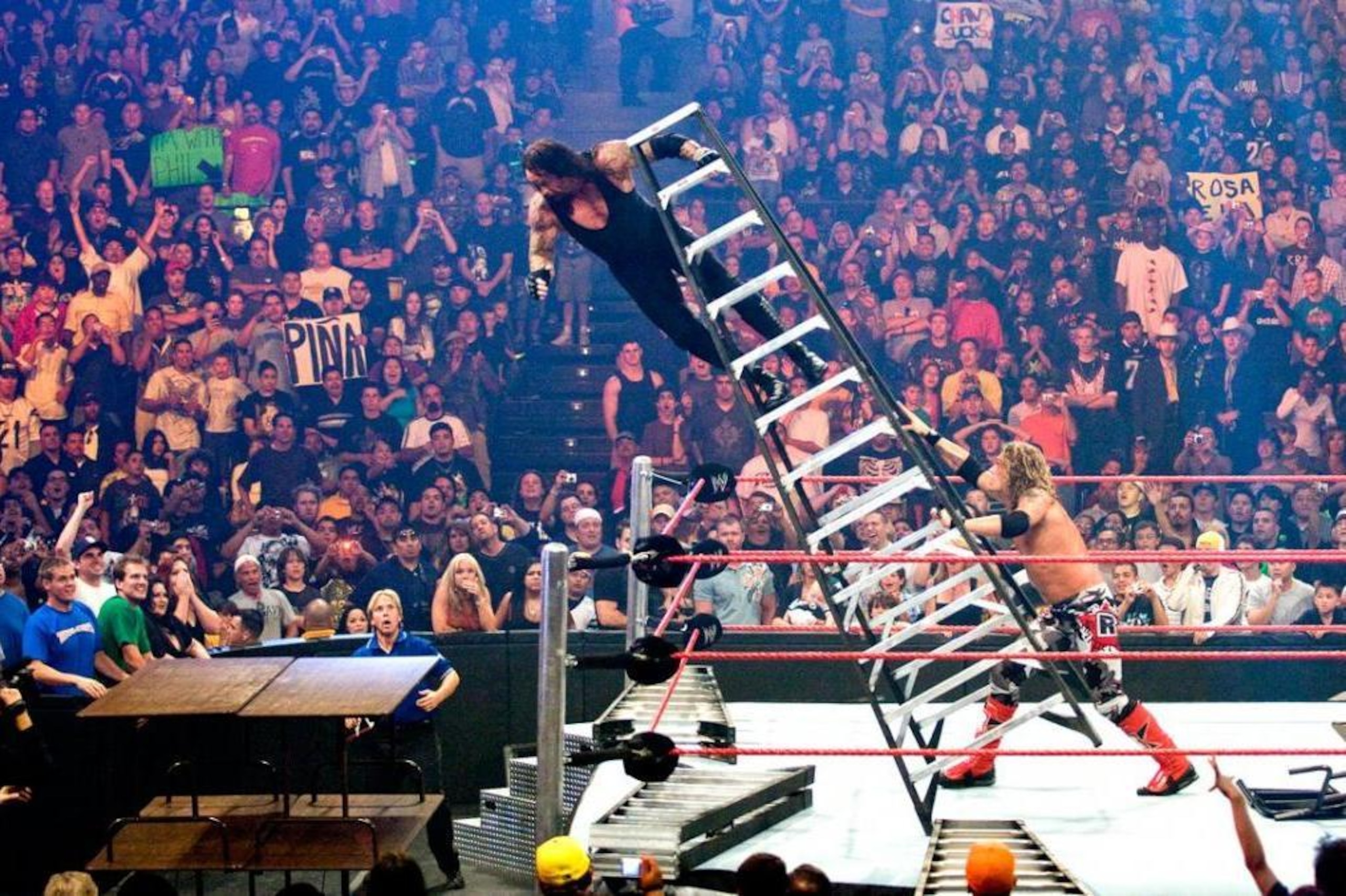 Edge pushing The Undertaker off of a ladder through some tables. Edge pushing The Undertaker off of a ladder through some tables.