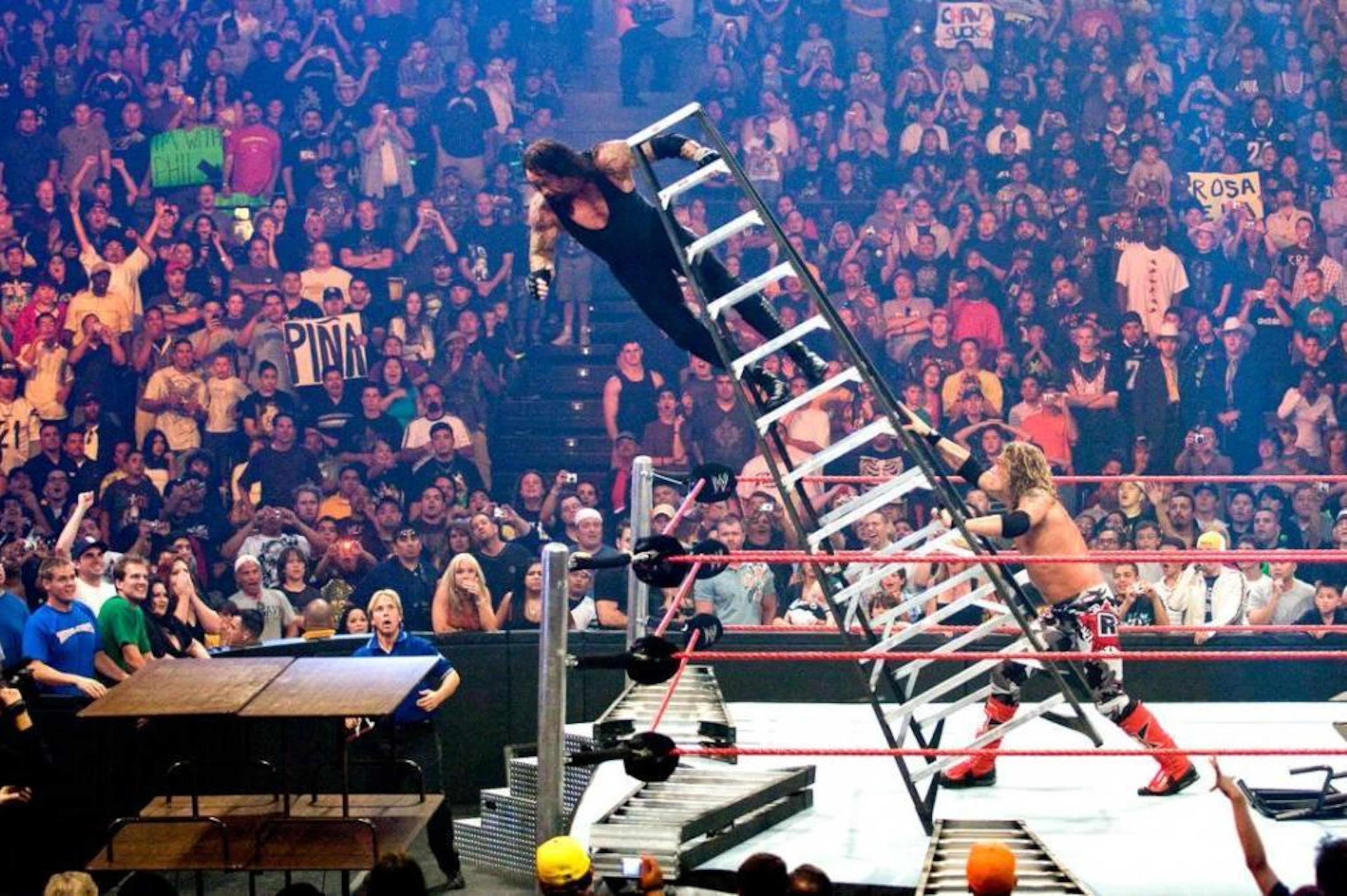 Edge pushing The Undertaker off of a ladder through some tables. Edge pushing The Undertaker off of a ladder through some tables.